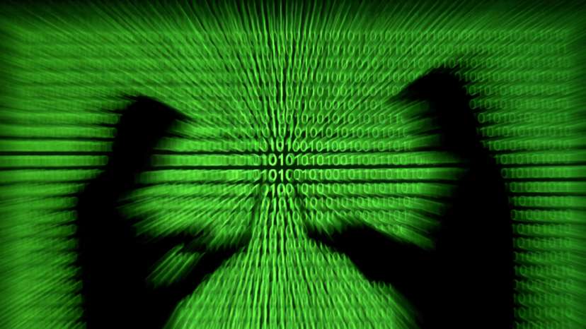 FILE PHOTO: Silhouettes of laptop users are seen next to a screen projection of binary code are seen in this picture illustration