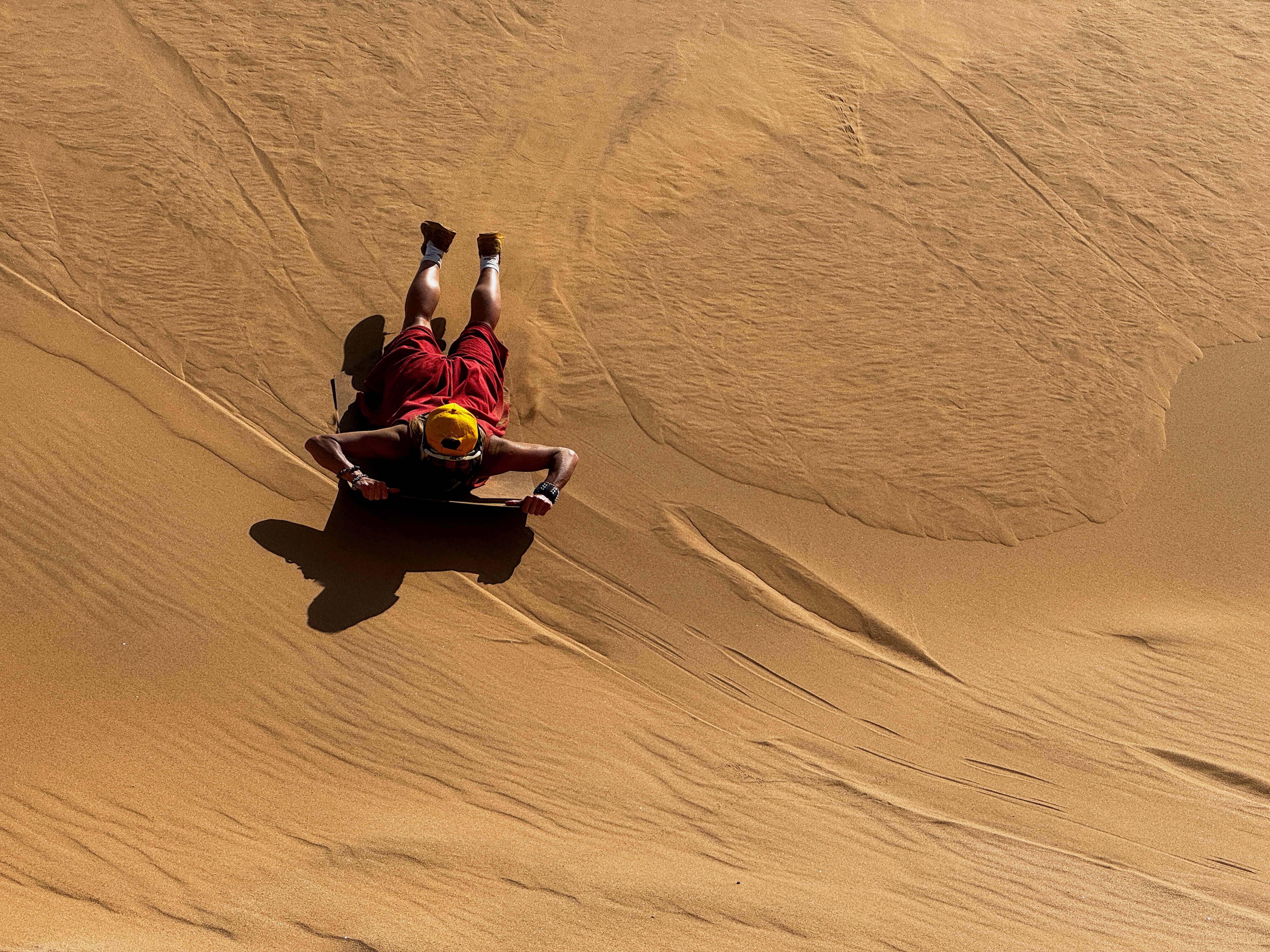 A tourist sandboards on the dunes in Walvis Bay