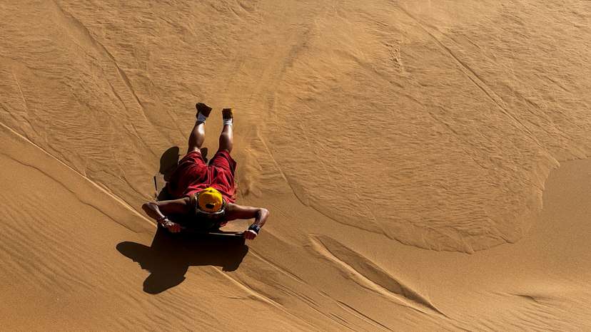 A tourist sandboards on the dunes in Walvis Bay