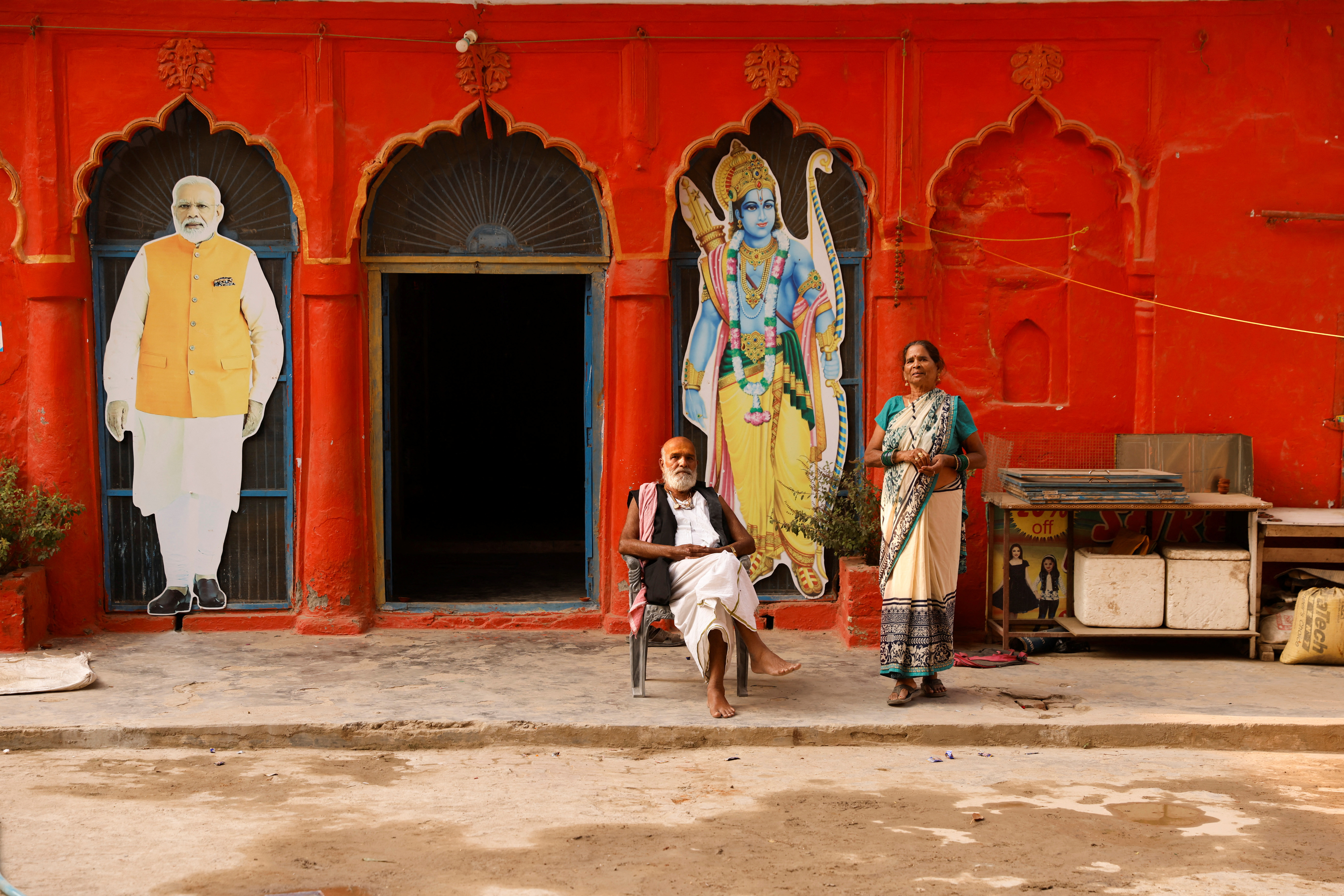 People are seen at the premises of a temple, next to the cutouts of India's Prime Minister Narendra Modi and the Hindu Lord Ram, in Ayodhya