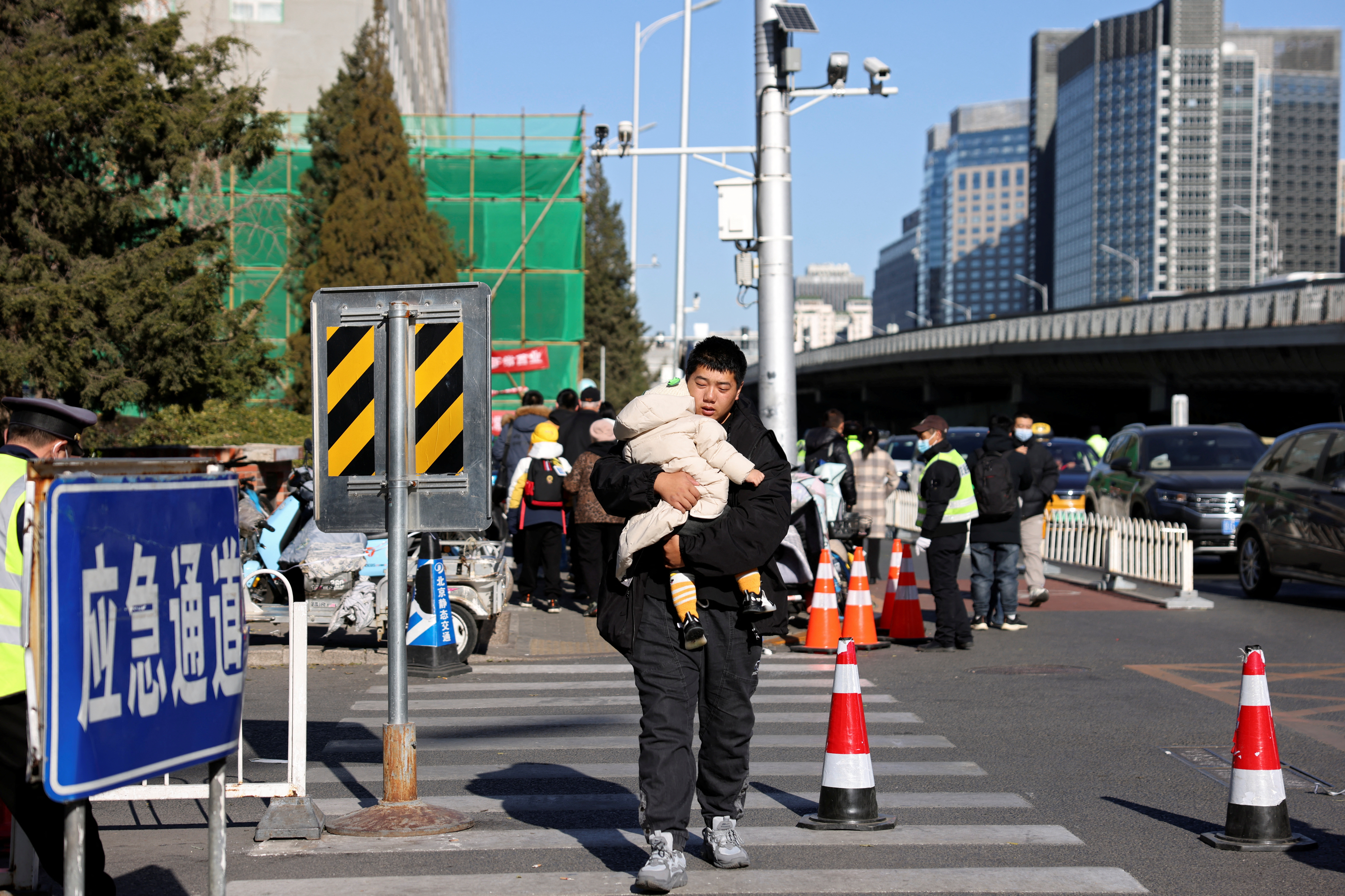 Man carries a child outside a children's hospital in Beijing