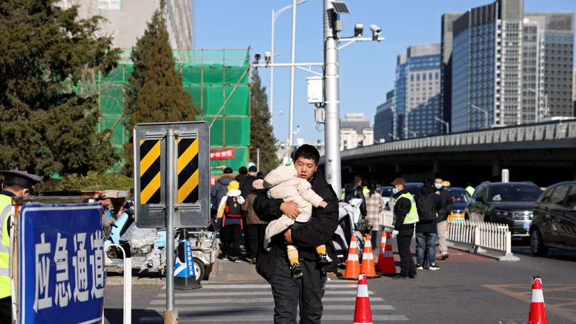 Man carries a child outside a children's hospital in Beijing