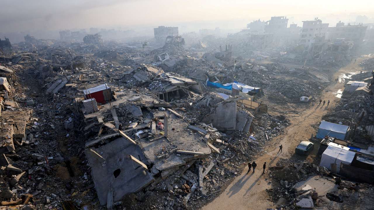 FILE PHOTO: Palestinians walk past the rubble of destroyed buildings, in Gaza City