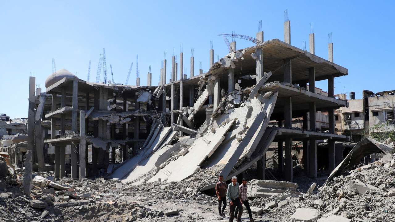 Palestinians walk past a destroyed building, as they inspect the damage in the aftermath of Israeli operation at Sabra neighbourhood in Gaza City