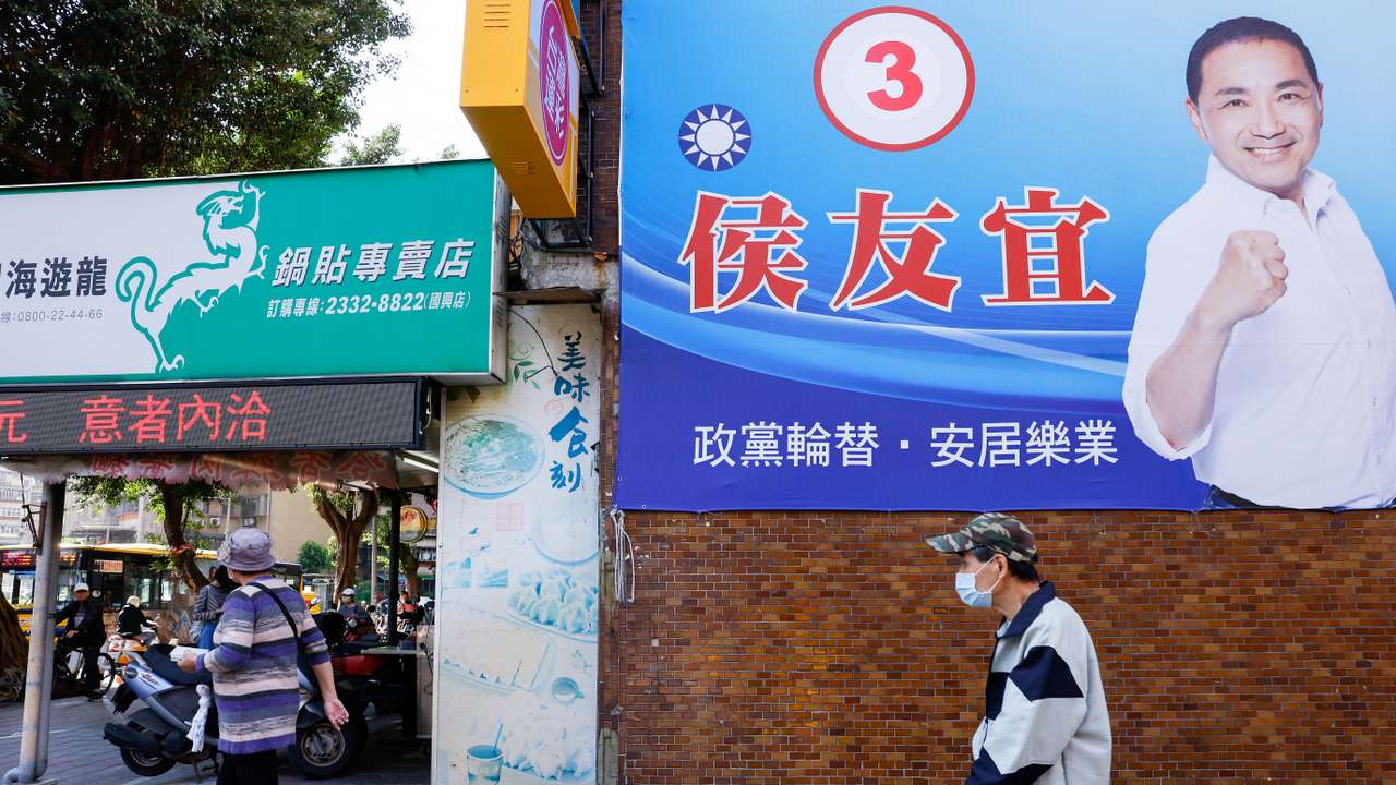 People walk past a campaign ad for Hou Yu-ih, a candidate for Taiwan's presidency, from the main opposition party Kuomintang (KMT)