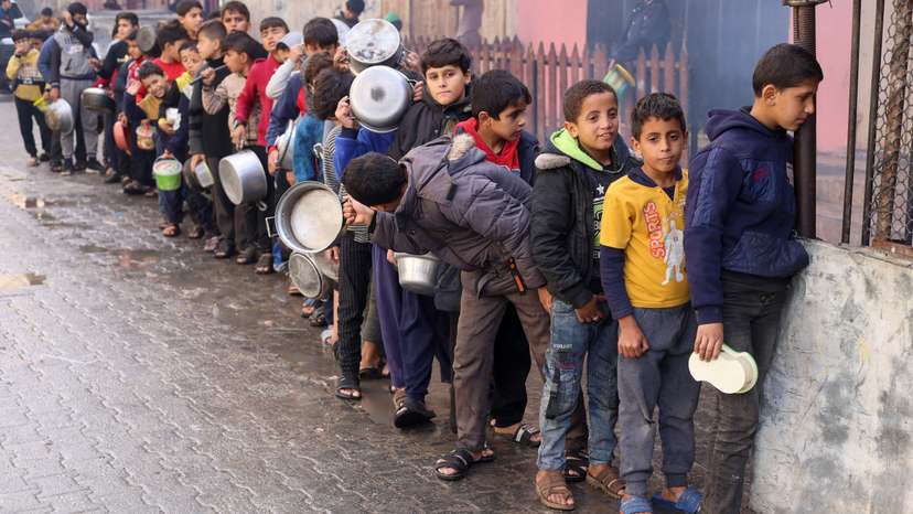 Palestinian children carry pots as they queue to receive food cooked by a charity kitchen, in Rafah in the southern Gaza Strip