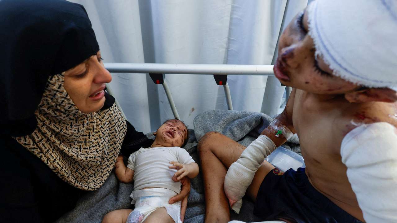 Palestinian child Tareq Qamar, who was injured in an Israeli strike that killed his mother, is carried by his aunt as his brother Mohammed who was wounded along with him reacts on a bed, at Nasser hospital, in Khan Younis in the southern Gaza Strip