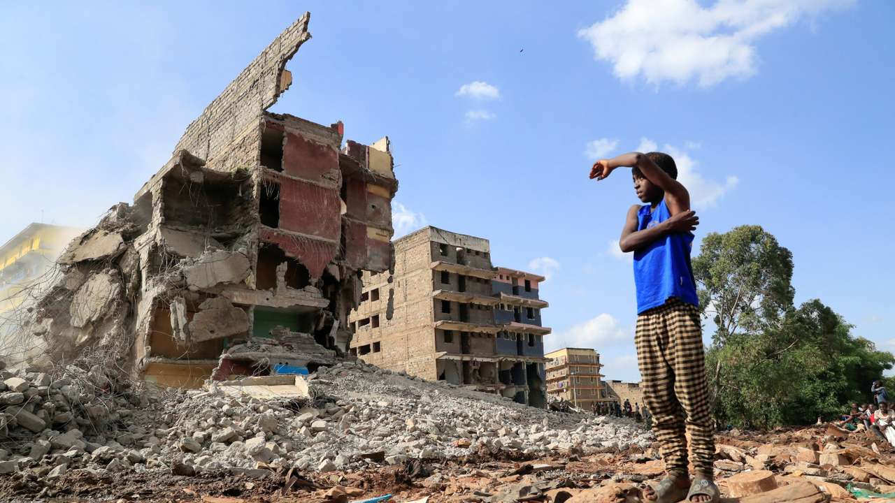 A boy looks at the search and rescue operations on the rubble of a residential flat built on riparian land, that collapsed while undergoing demolition in Nairobi