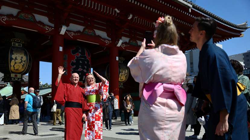 Tourists pose for a photograph near Sensoji temple at Asakusa district in Tokyo