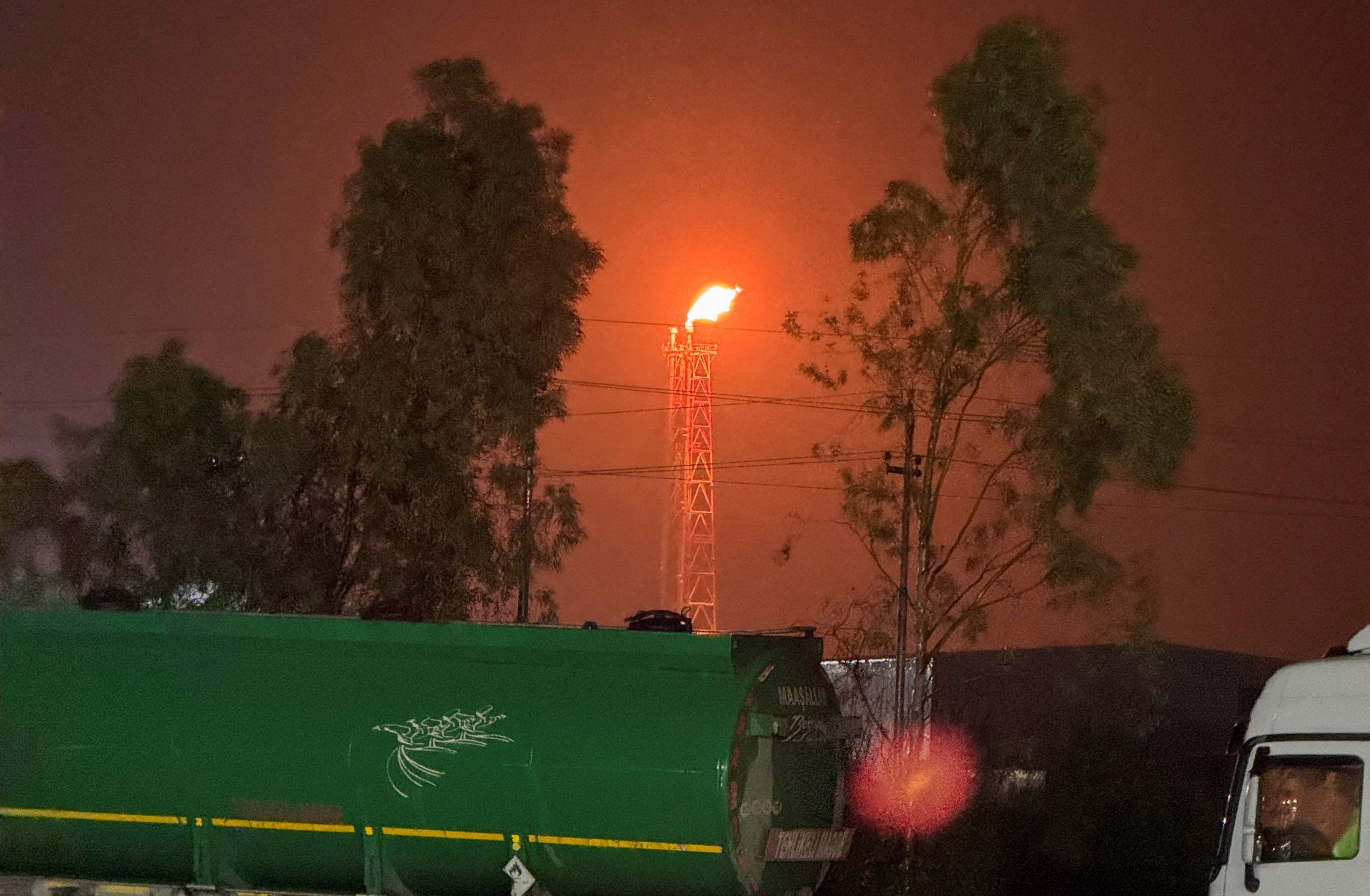 A gas flare burns at the Lanaz refinery after it was targeted by a drone strike, in Erbil