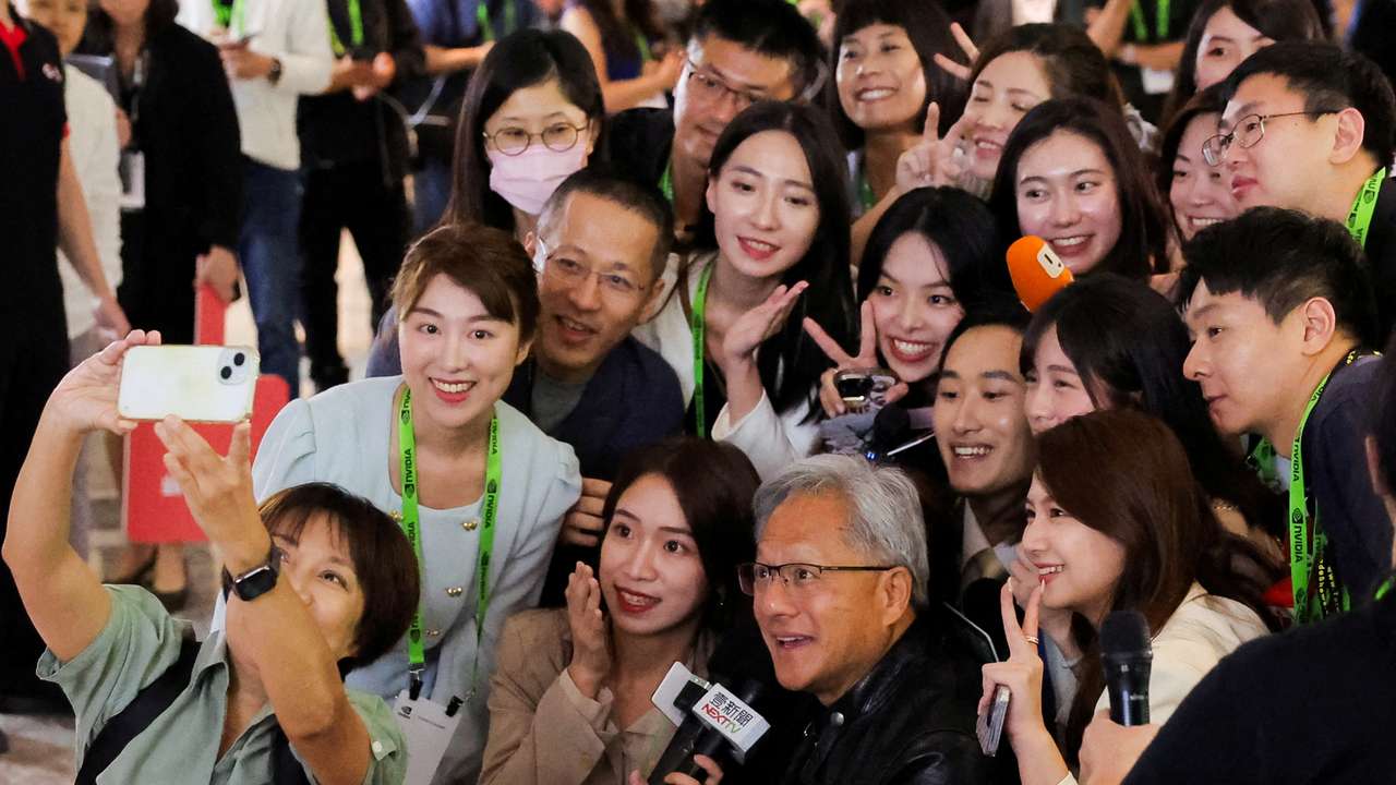FILE PHOTO: Nvidia CEO Jensen Huang poses for selfie with members of the media at COMPUTEX forum in Taipei