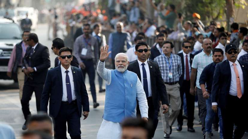 FILE PHOTO: PM Modi waves to his supporters as he arrives to cast his vote, in Ahmedabad