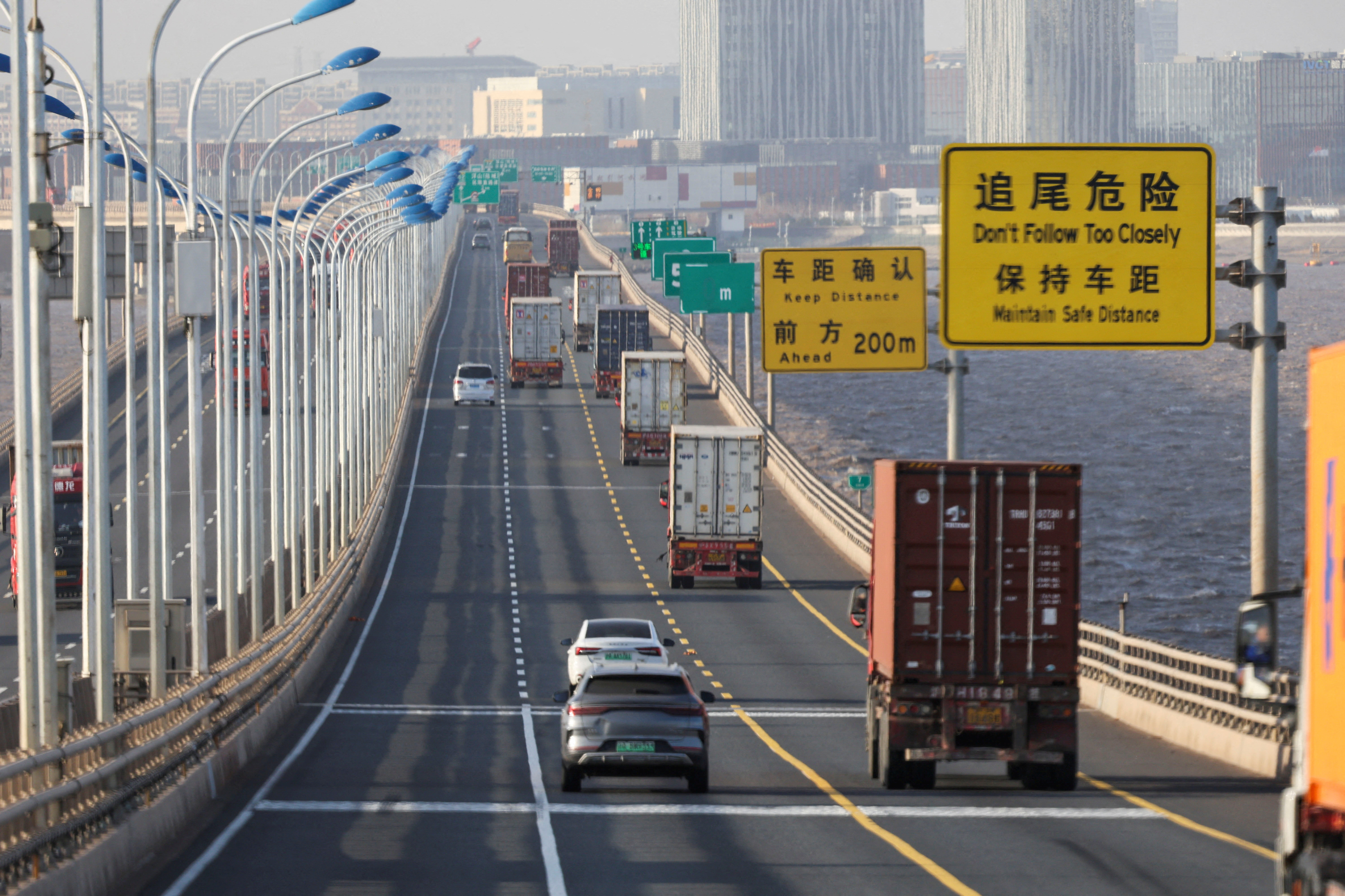 Trucks loaded with shipping containers pass over Donghai Bridge to exit Yangshan Port outside of Shanghai