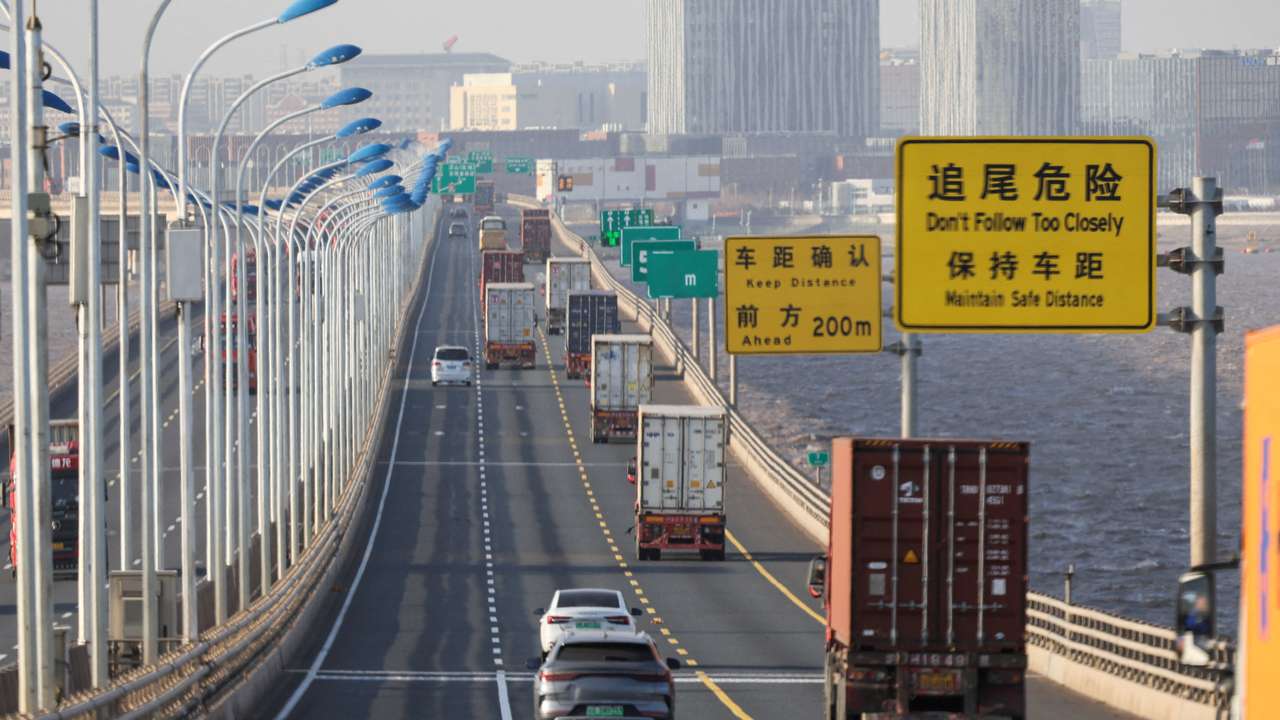 Trucks loaded with shipping containers pass over Donghai Bridge to exit Yangshan Port outside of Shanghai