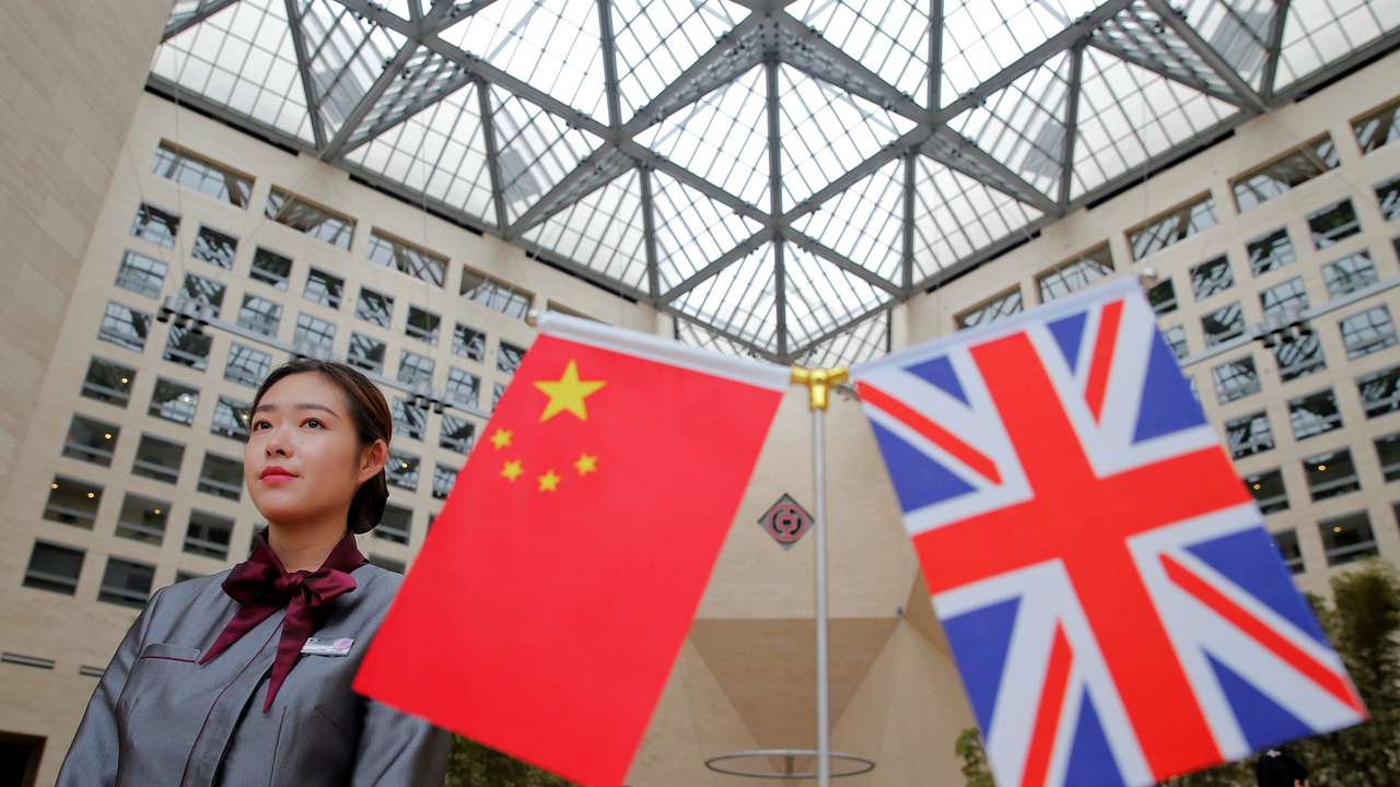A member of staff waits behind flags at the Bank of China head office building in Beijing