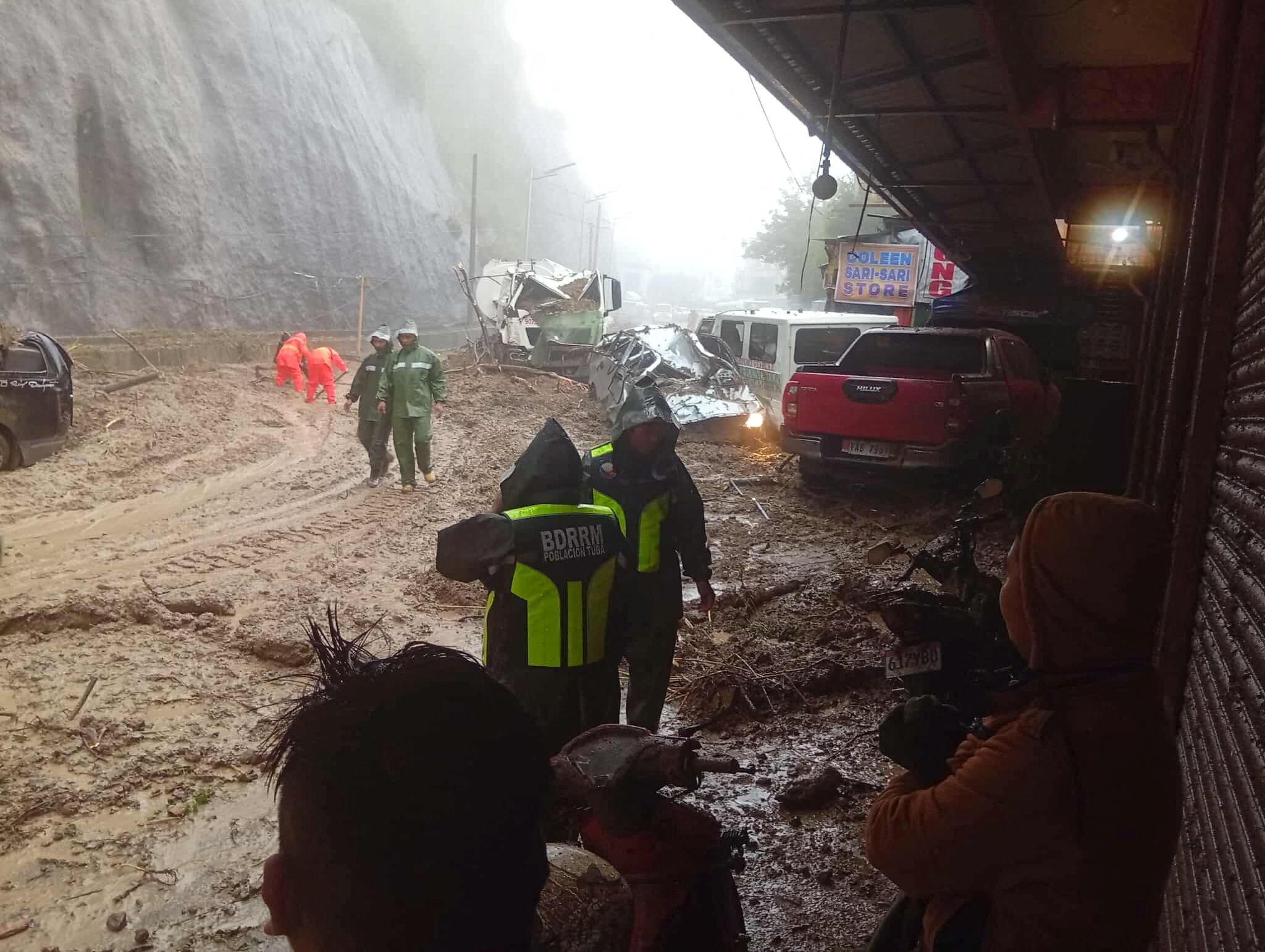 Rescue workers take part in a road clearing operation after a landslide in Tuba, Benguet Province