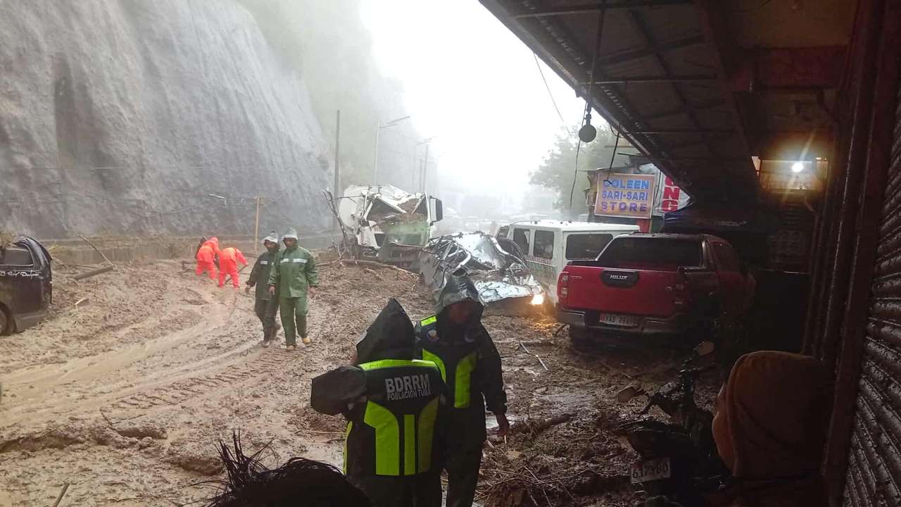Rescue workers take part in a road clearing operation after a landslide in Tuba, Benguet Province