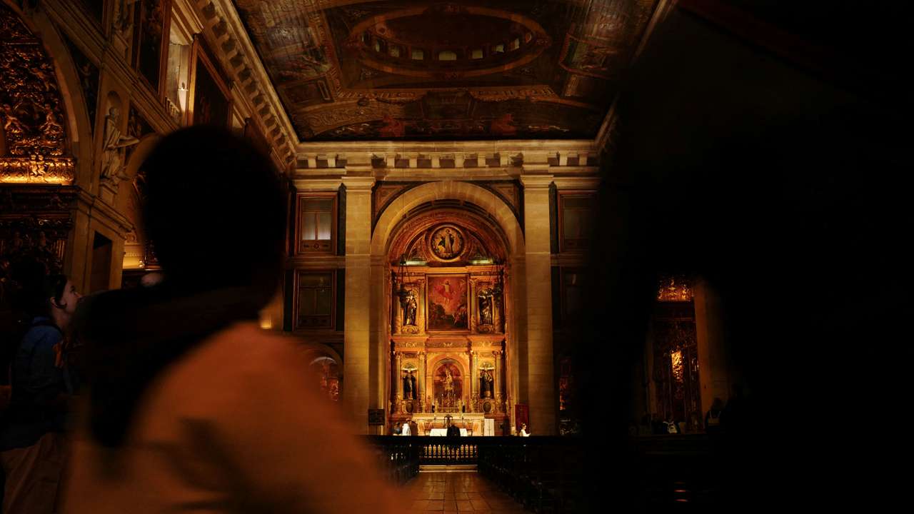 A child passes by while holding an adult hand inside a church in Lisbon