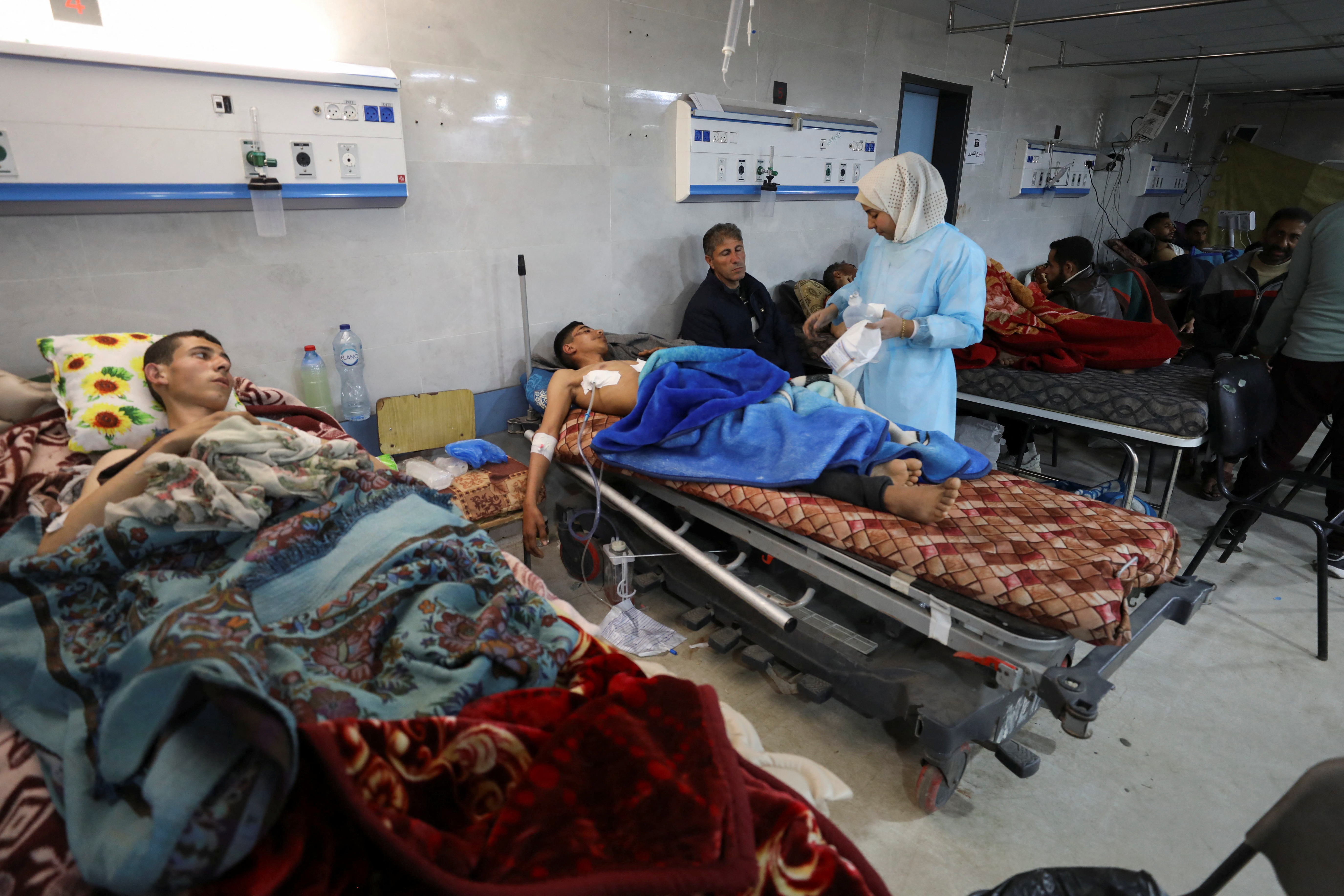 Palestinians who were wounded in Israeli fire while waiting for aid, according to health officials, lie on beds at Al Shifa hospital, amid the ongoing conflict between Israel and Hamas, in Gaza City