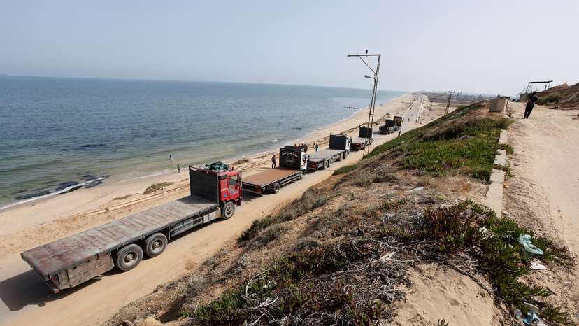 Trucks move towards a U.S.-built pier where they will be loaded with aid, as seen from central Gaza Strip