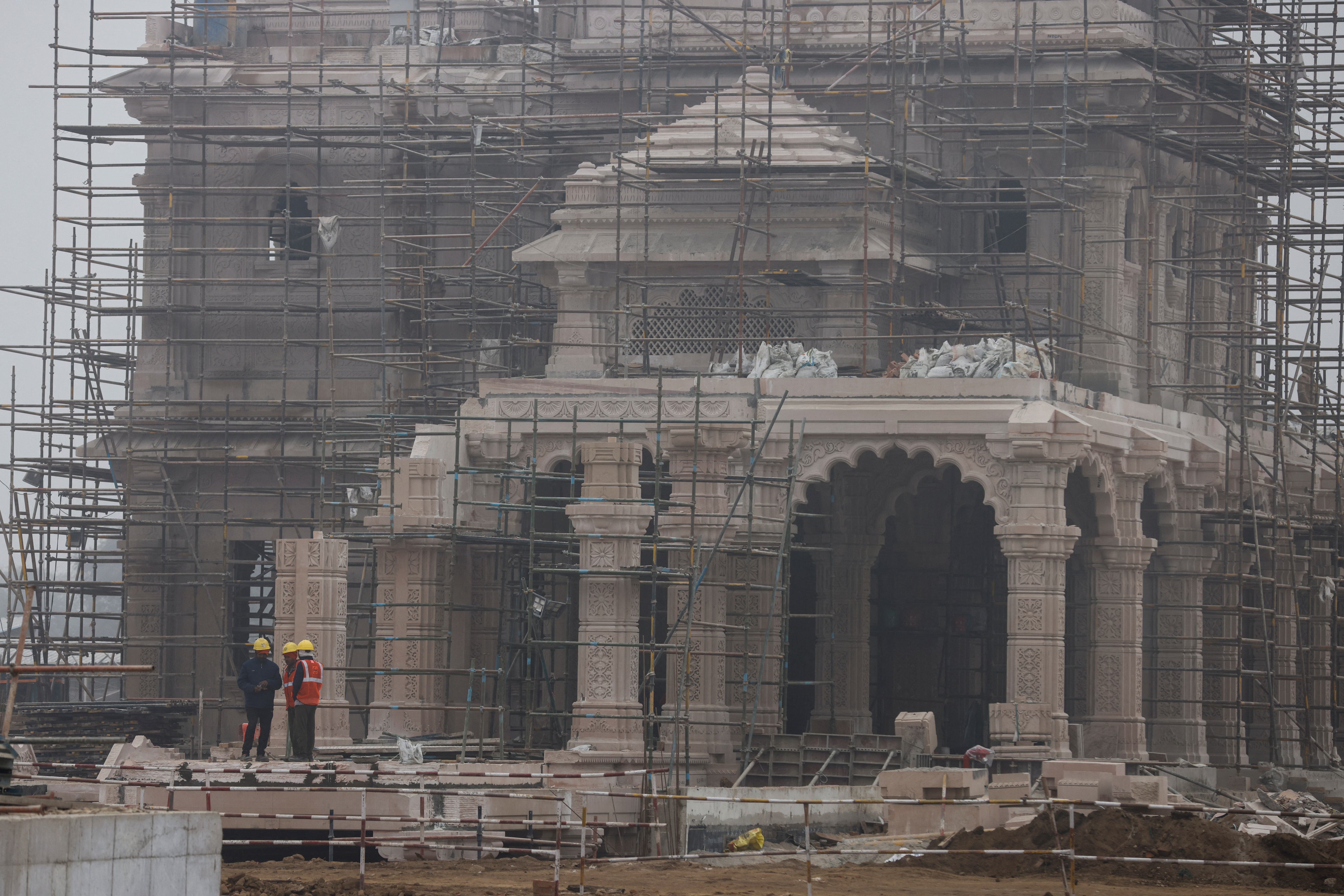 Workers stand in front of the under construction site of the Hindu Ram Temple in Ayodhya