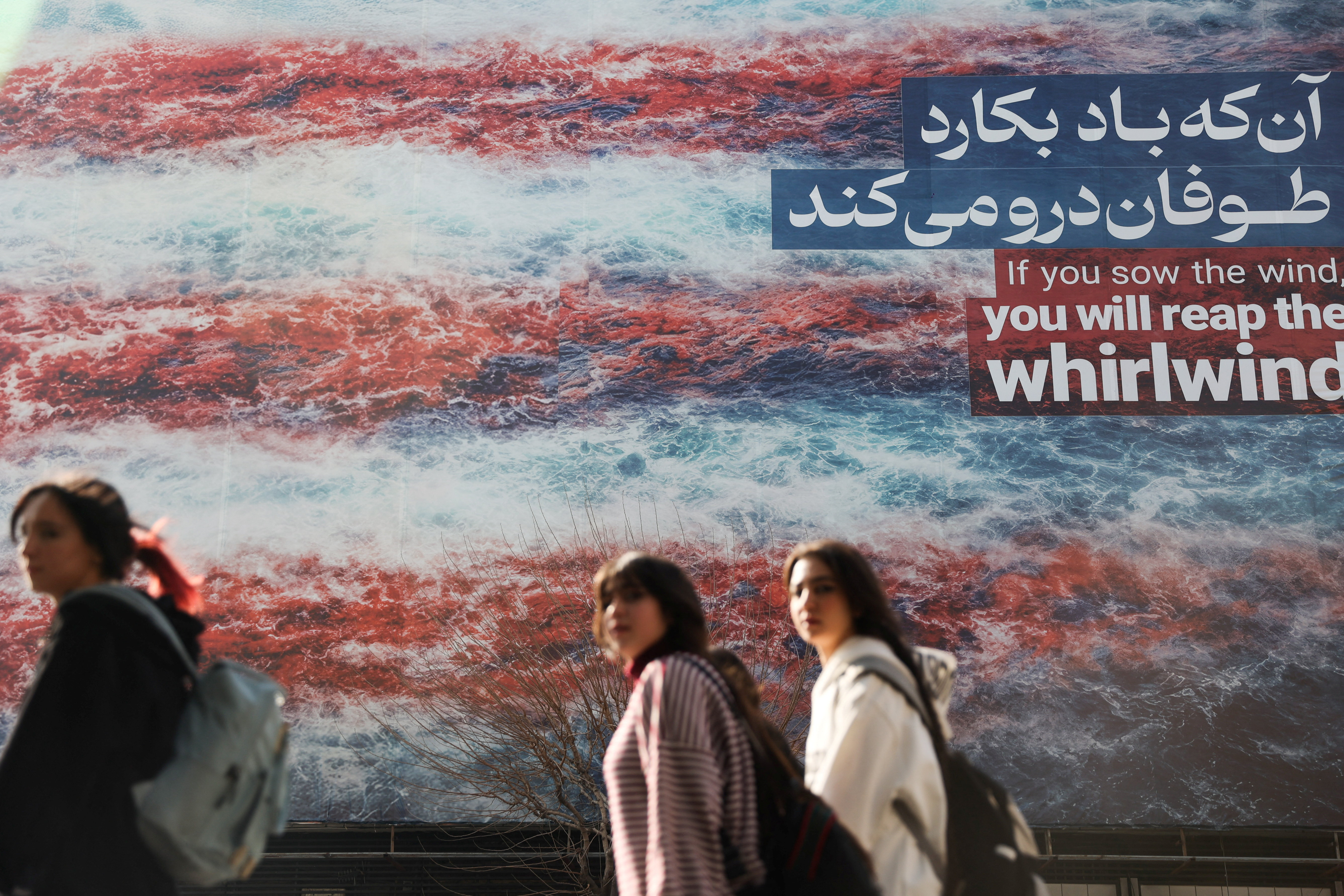 Iranian women walk past an anti-U.S. billboard in Tehran