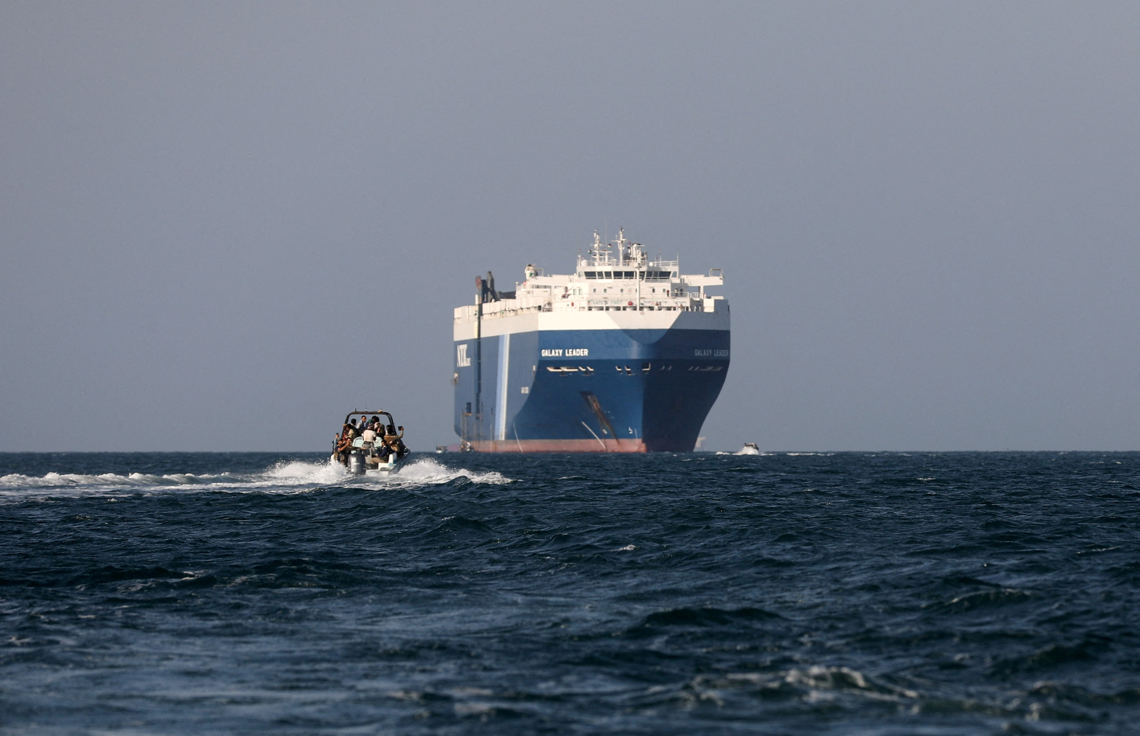 FILE PHOTO: Boat carrying people sails near the Galaxy Leader commercial ship, seized by Yemen's Houthis last month, off the coast of in al-Salif