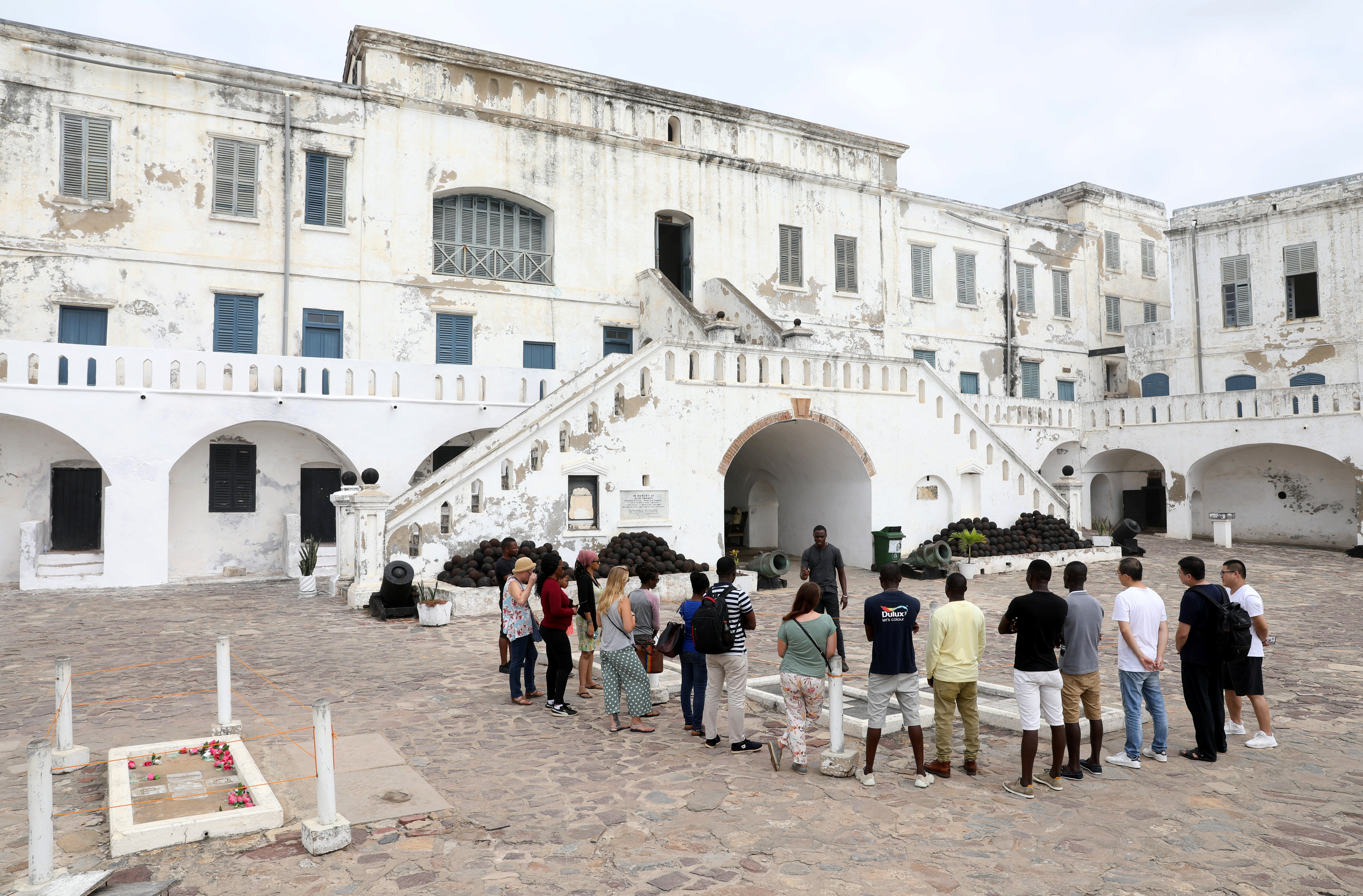 Foreign tourists listen to a guide at the Cape Coast Slave Castle in Ghana, July 28, 2019. Cape Coast Castle was used as a slaving post from where slaves were bought and sold and then shipped to the U.S. and other countries. The 400-year anniversary of the first slave boat to arrive in America from Africa has caused a rush of interest in heritage tourism in West Africa, as ancestors go back to ancient sites to delve into a dark and often hidden past. Picture taken july 28, 2019.   REUTERS/Siphiwe Sibeko