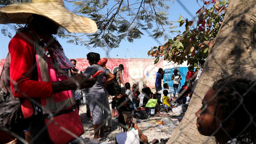 FILE PHOTO: People fleeing violence gather outside a Haitian National Police station, in Port-au-Prince