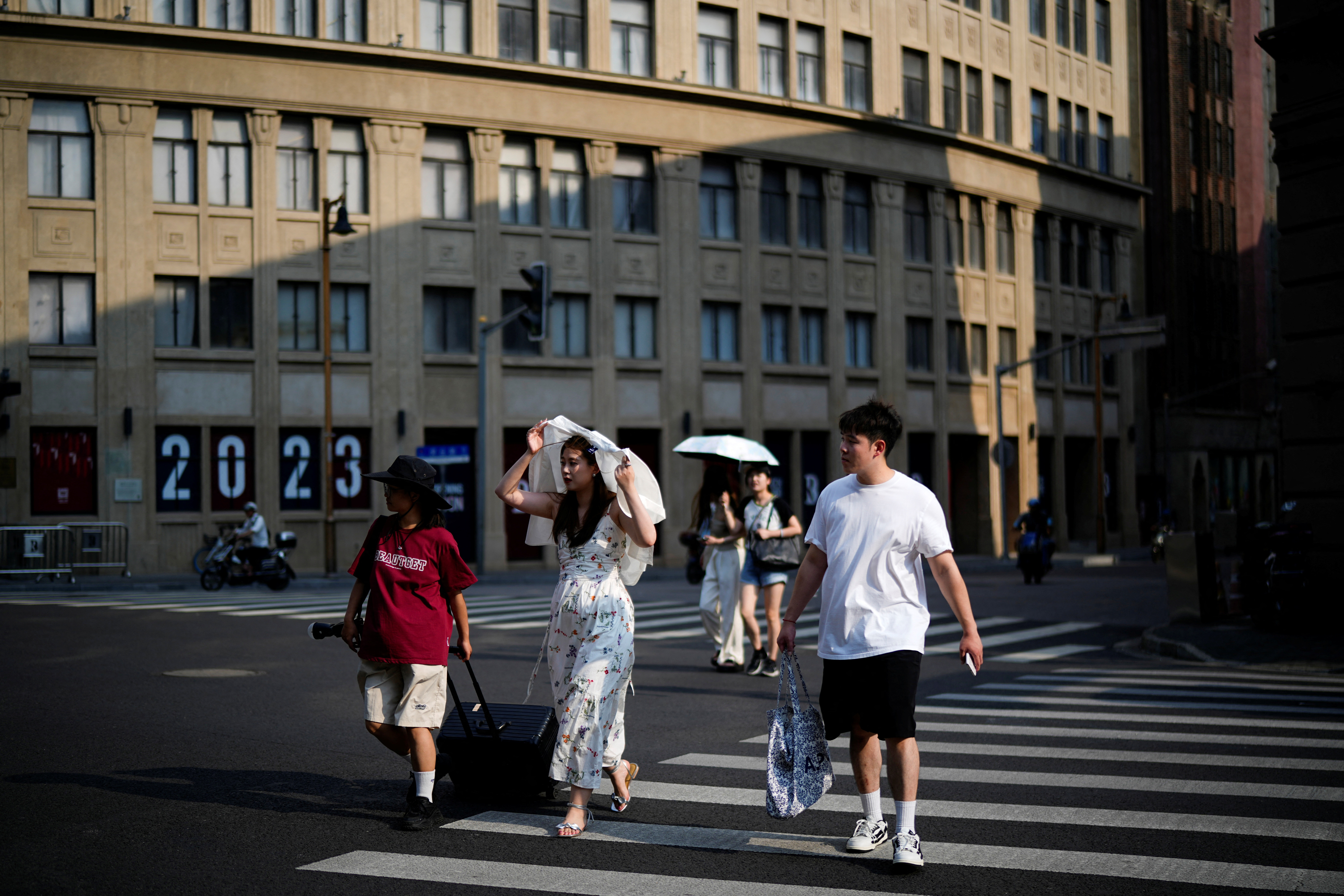 People cross a street amid an alert for heatwave, in Shanghai