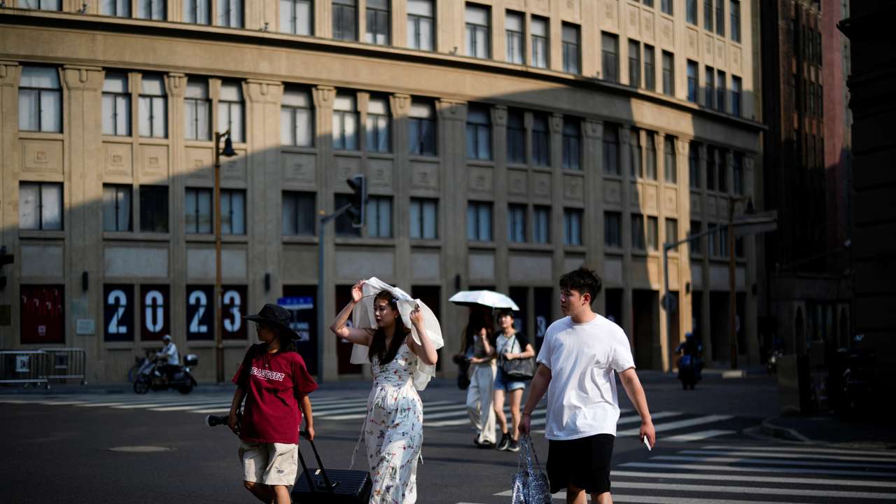 People cross a street amid an alert for heatwave, in Shanghai