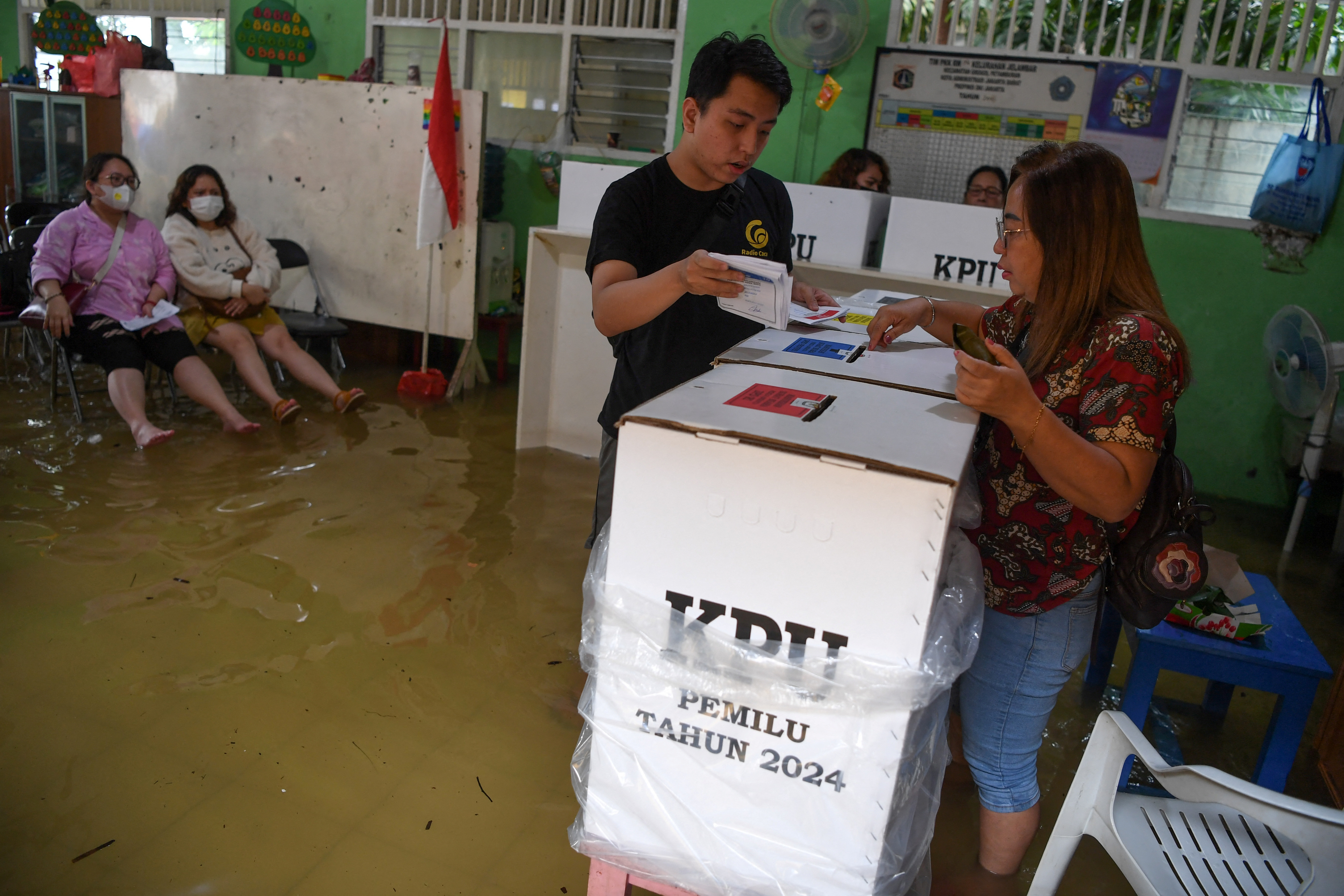 Voters cast their ballots at a flooded polling station during general election in Jelambar