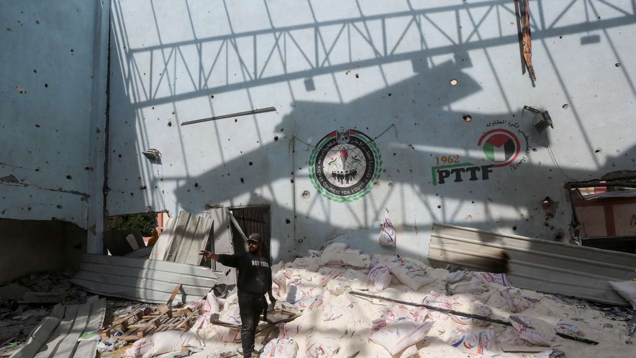 Palestinians inspect the site of an Israeli strike on an aid warehouse, in Al-Nuseirat refugee camp