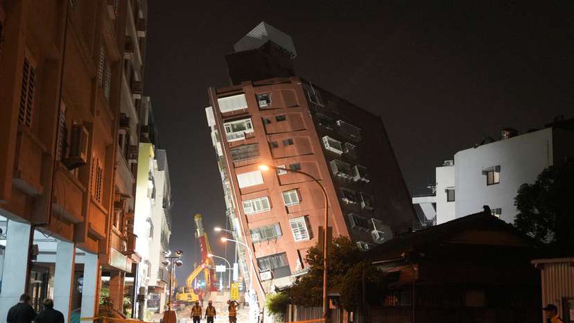 Workers walk at the site where a building collapsed following an earthquake, in Hualien