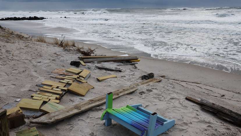 A chair lays on the sand with other debris as waves rush the beach during the pass of a winter storm in Lido beach, New York