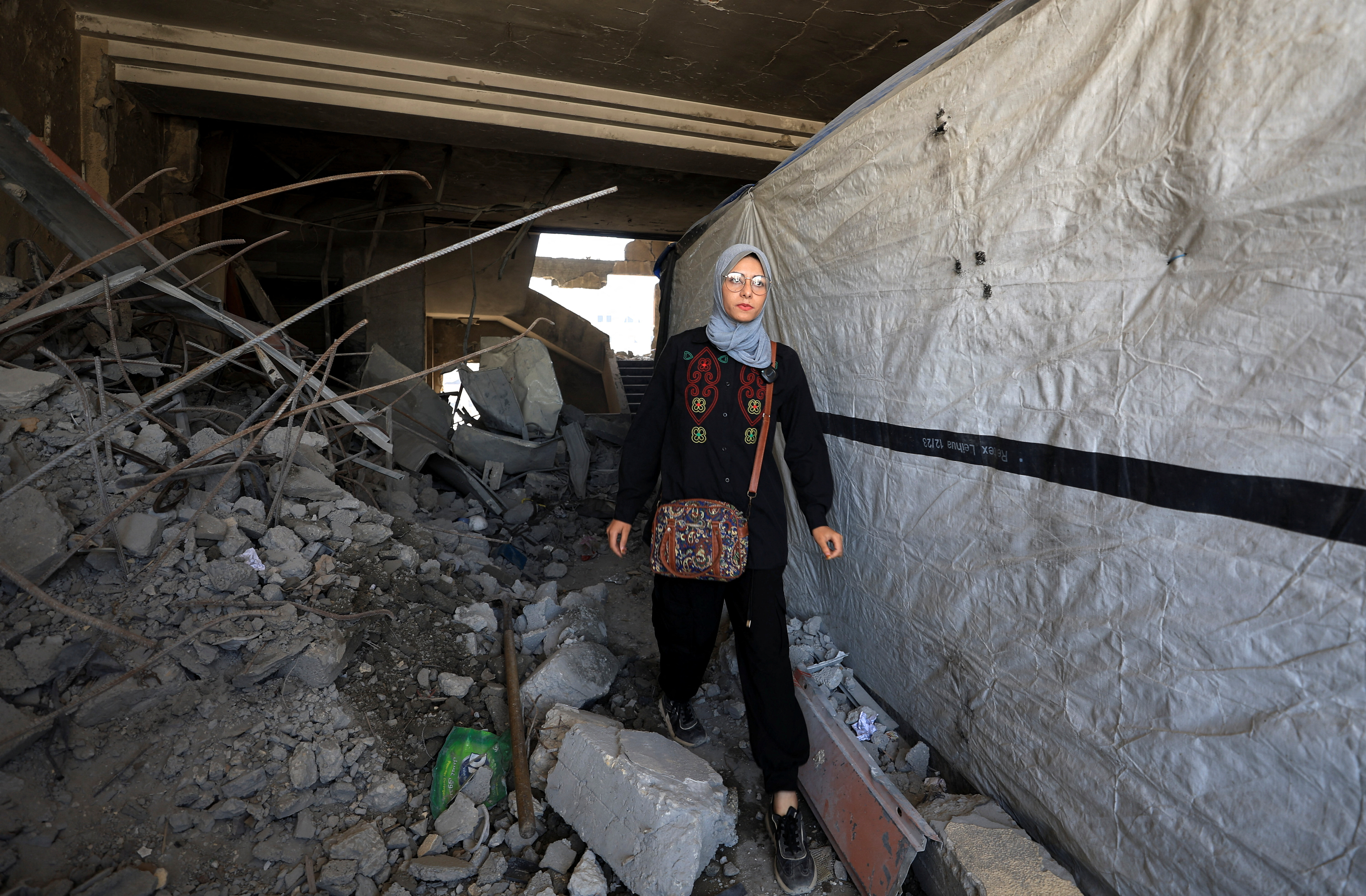 Maha Ali walks inside the damaged Islamic University of Gaza, where she shelters, in Gaza City