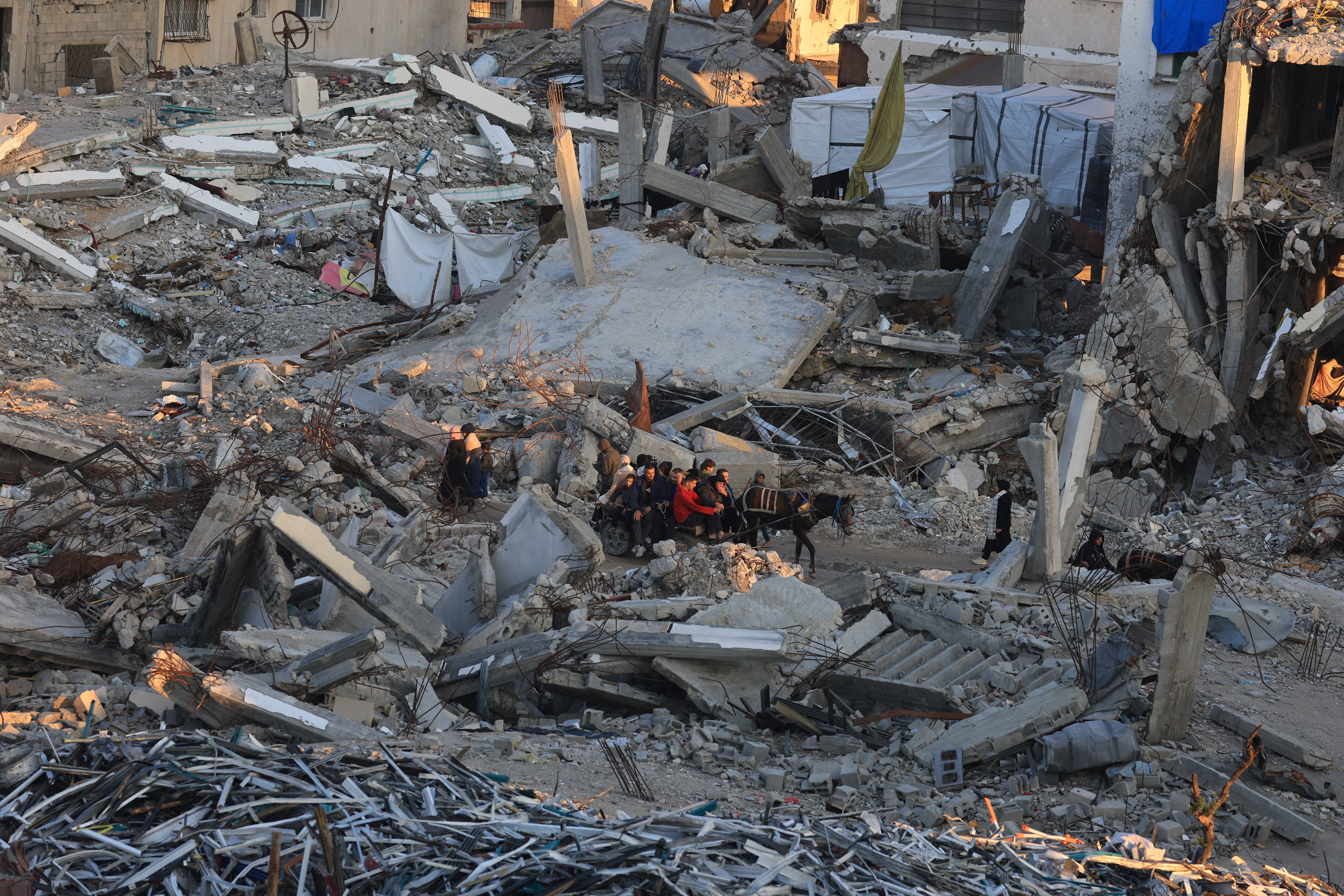 Palestinians move past the rubble of residential buildings destroyed during the war, in Gaza City