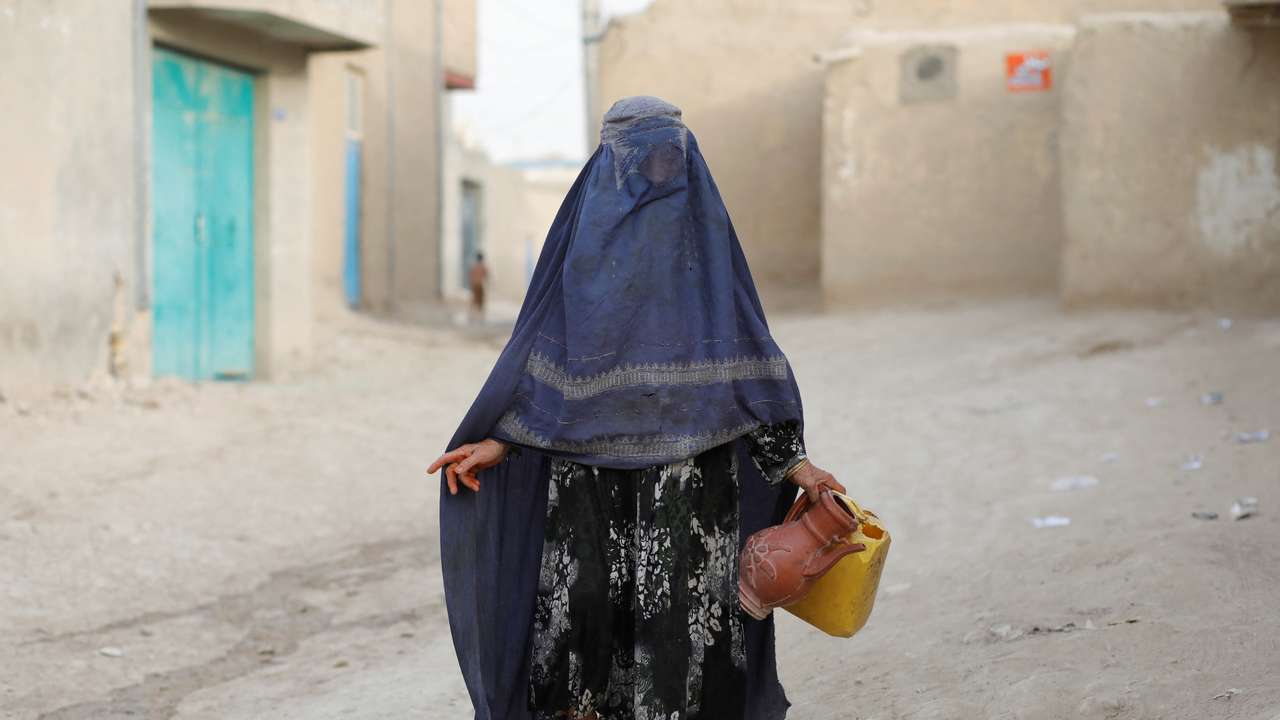 An Afghan woman carries empty containers to fetch water in Nahr-e-Shahi district in Balkh province
