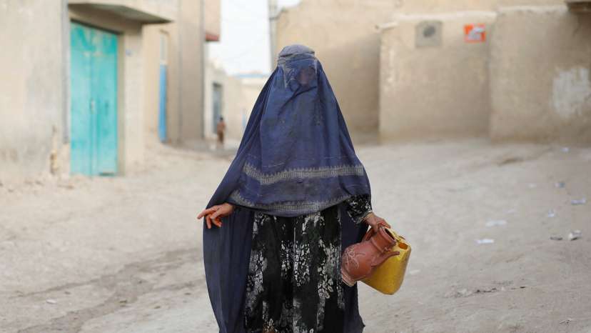 An Afghan woman carries empty containers to fetch water in Nahr-e-Shahi district in Balkh province