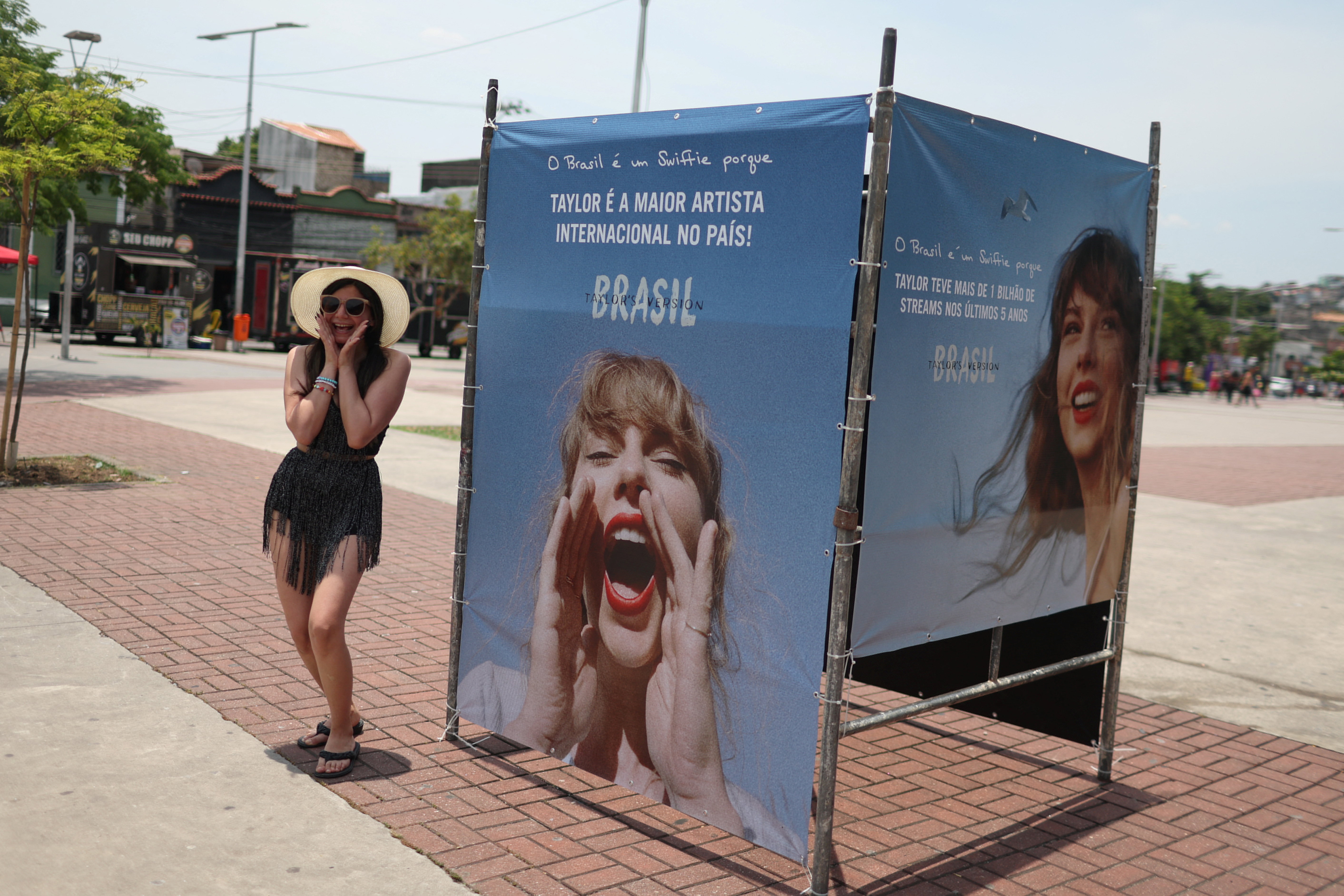 A girl poses next to a photo of singer Taylor Swift, before a concert in Rio de Janeiro