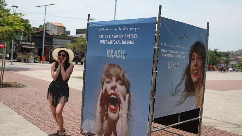 A girl poses next to a photo of singer Taylor Swift, before a concert in Rio de Janeiro