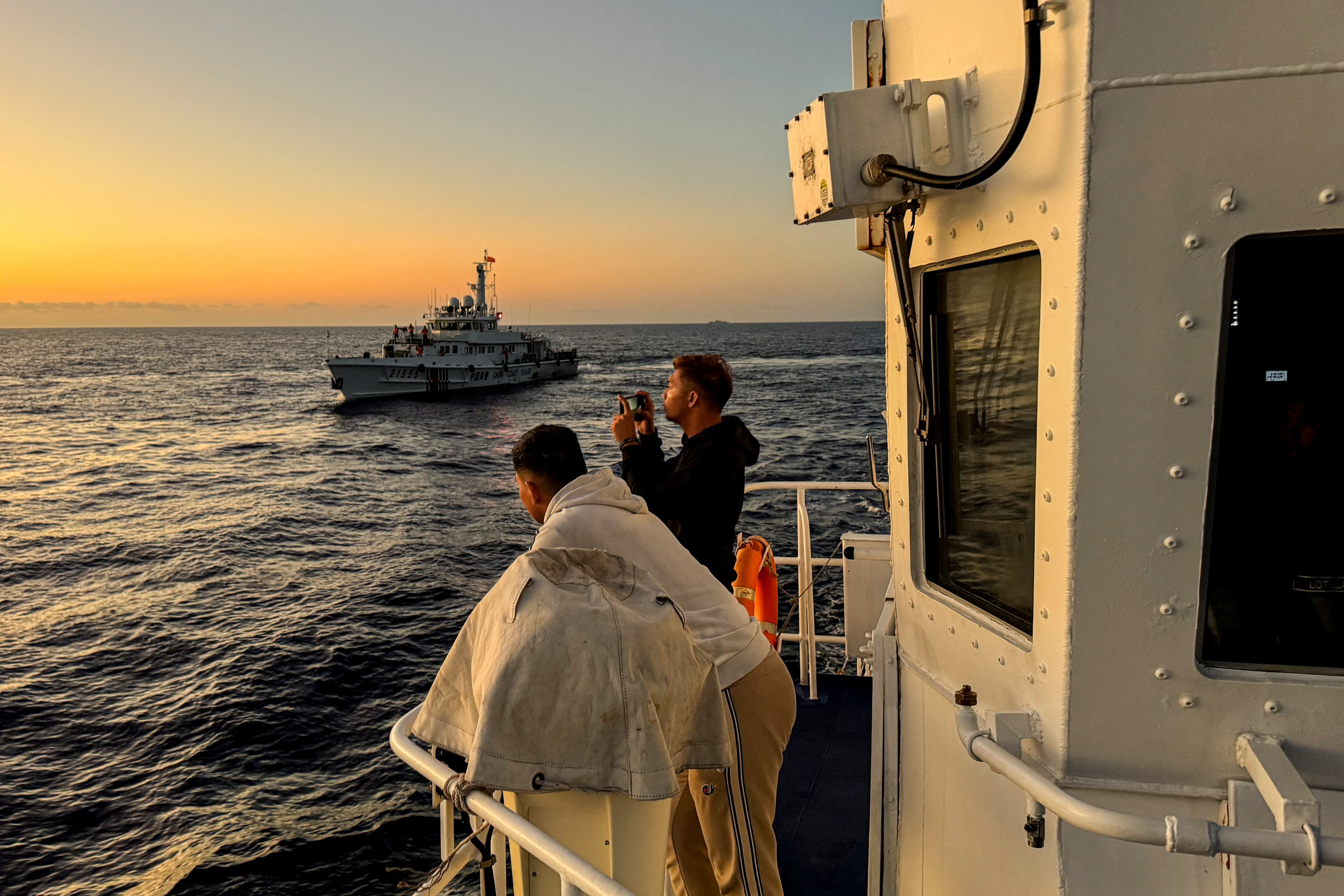 Philippine Coast Guard personnel documents a Chinese Coast Guard vessel shadowing the Philippine's resupply mission at Second Thomas Shoal in the South China Sea