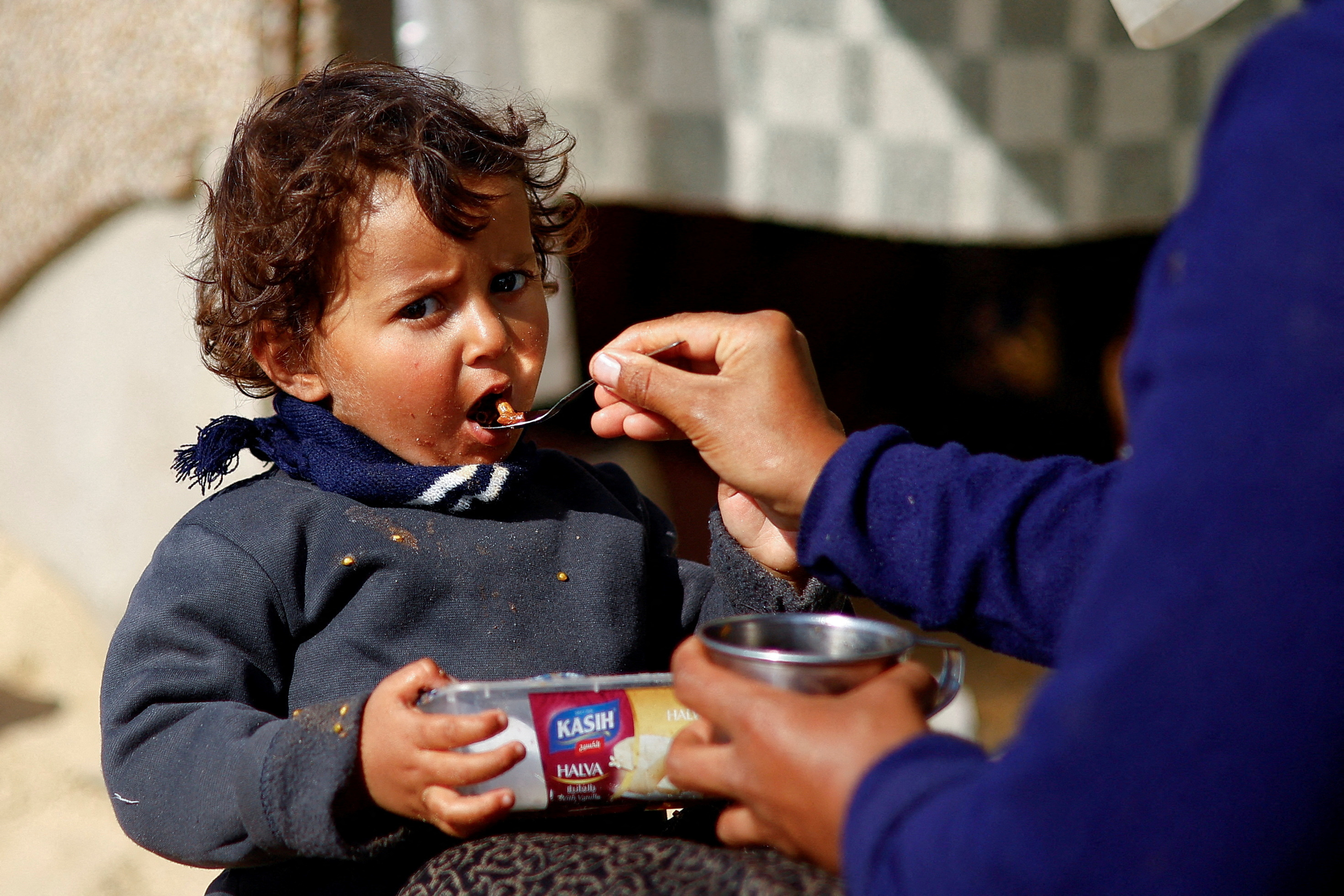 A displaced Palestinian child, who fled due to Israeli strikes, eats, amid the ongoing conflict between Israel and Hamas, in Rafah in the southern Gaza Strip