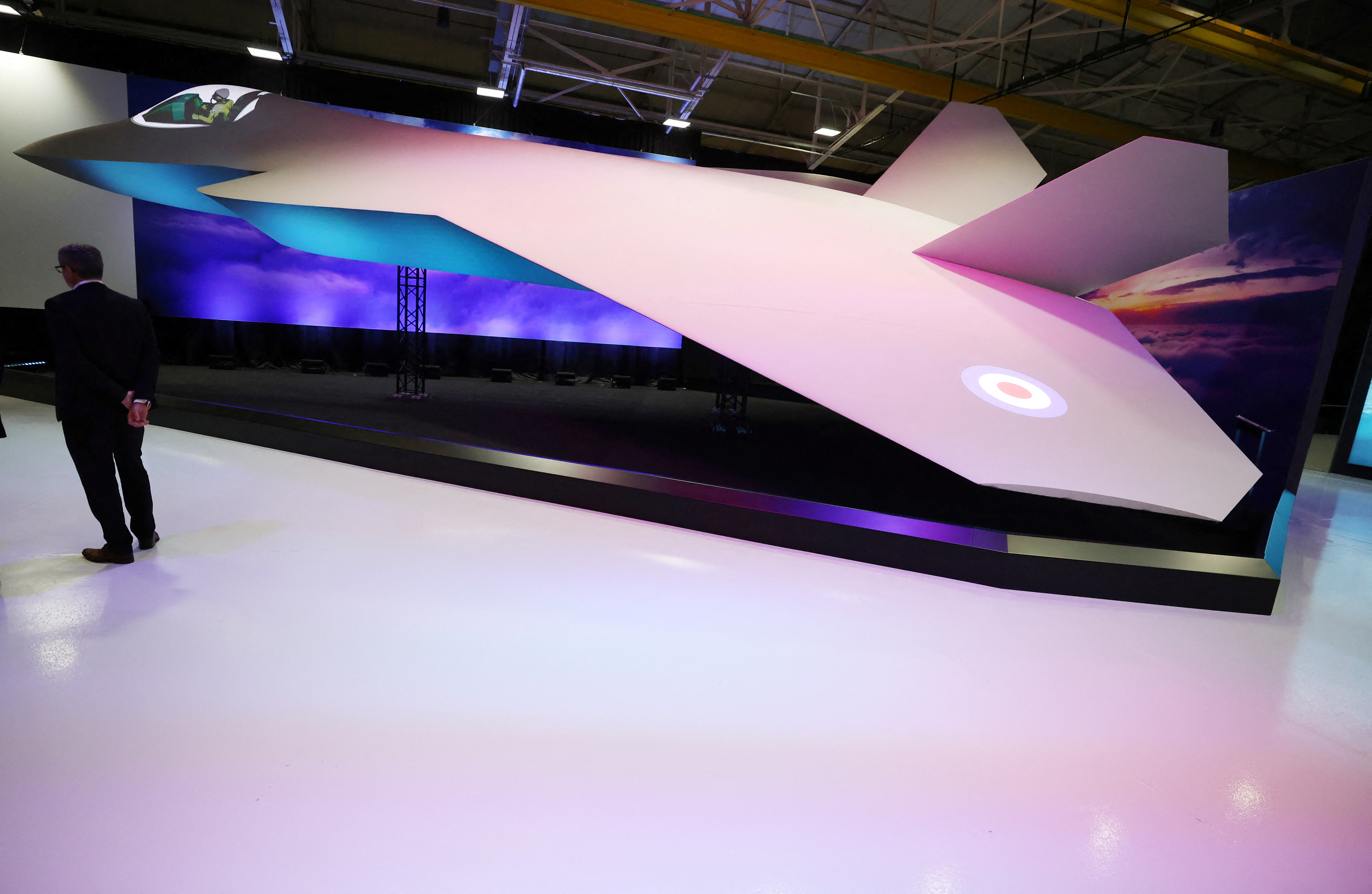A member of staff stands next to a concept model of the new GCAP (Global Combat Air Programme) 6th generation military jet at the BAE Systems Warton factory in Warton