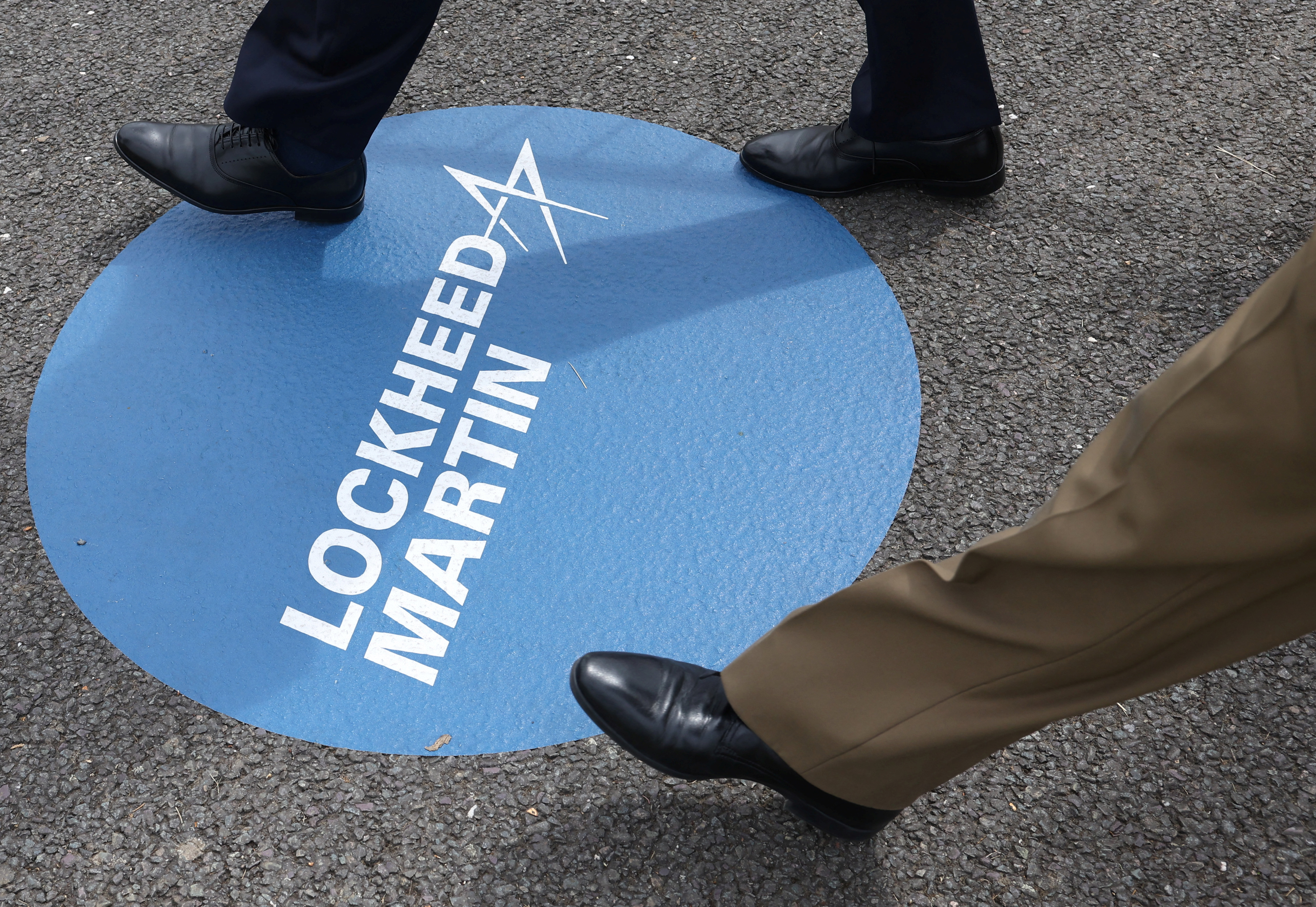Attendees walk over branding for Lockheed Martin at Farnborough International Airshow, in Farnborough