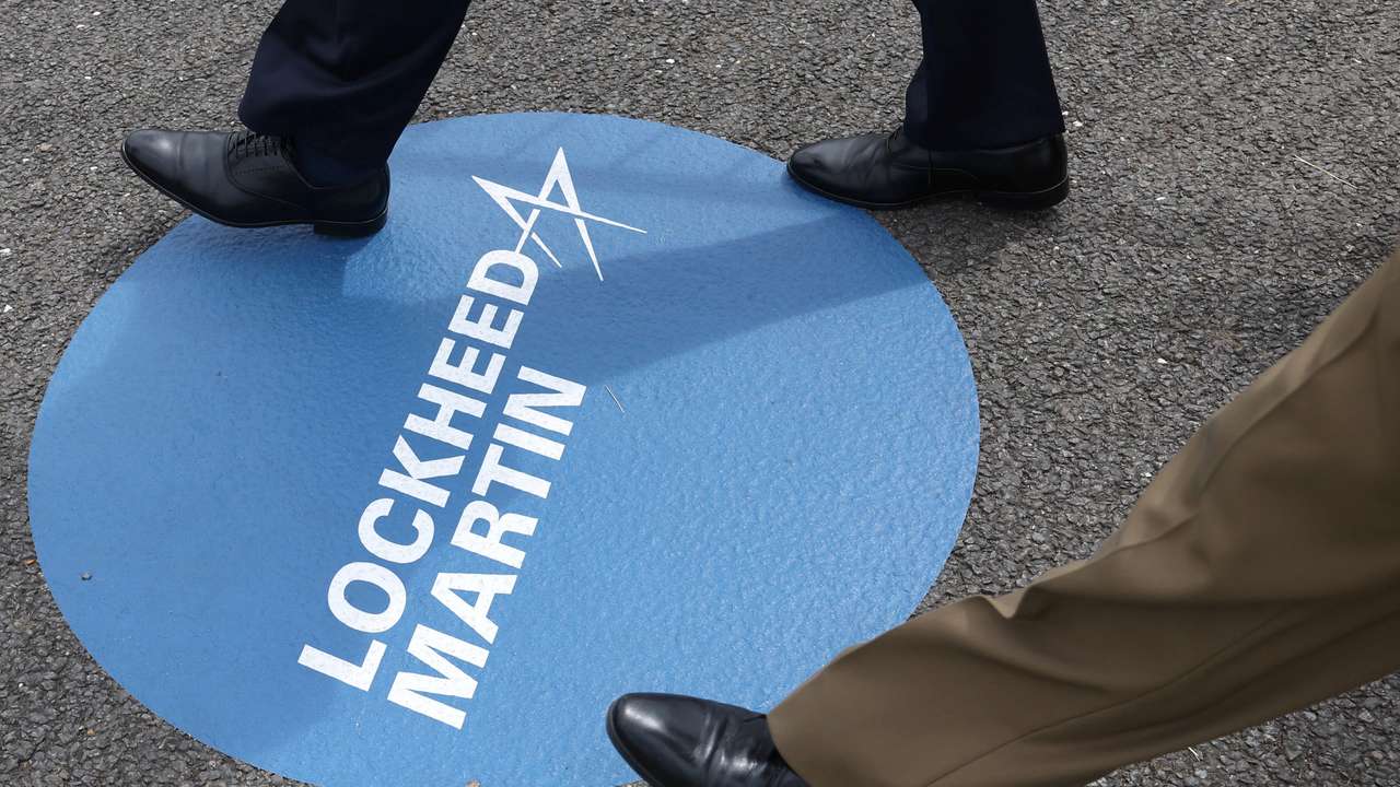 Attendees walk over branding for Lockheed Martin at Farnborough International Airshow, in Farnborough