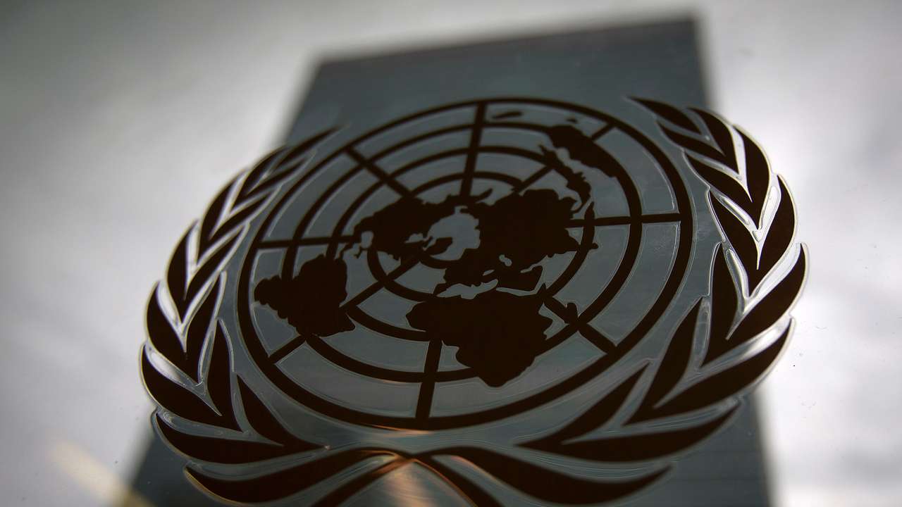 The United Nations headquarters building is pictured though a window with the UN logo in the foreground in the Manhattan borough of New York