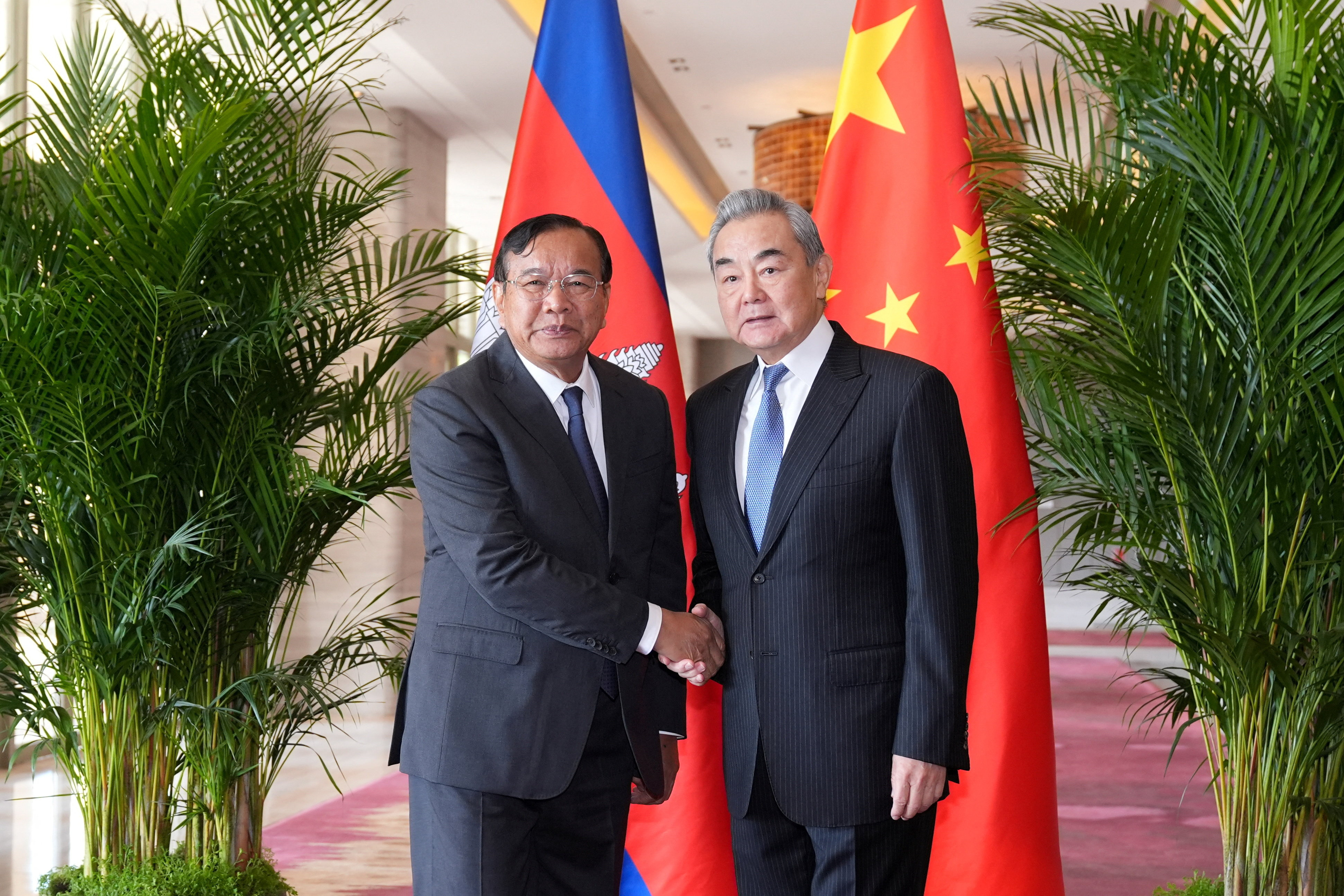 Chinese Foreign Minister Wang Yi shakes hands with Cambodian Deputy Prime Minister and Foreign Minister Prak Sokhonn in Yuxi