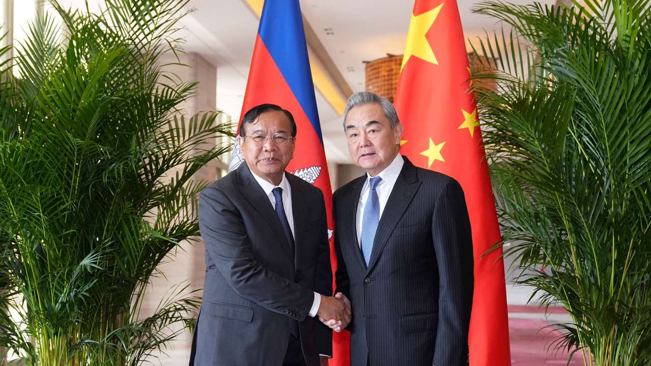 Chinese Foreign Minister Wang Yi shakes hands with Cambodian Deputy Prime Minister and Foreign Minister Prak Sokhonn in Yuxi