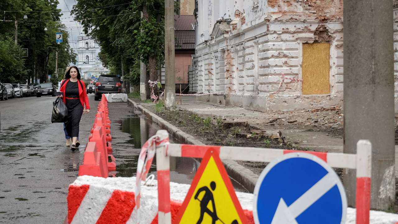 A resident walks at a street near a building damaged by Russian missile strikes in Sumy